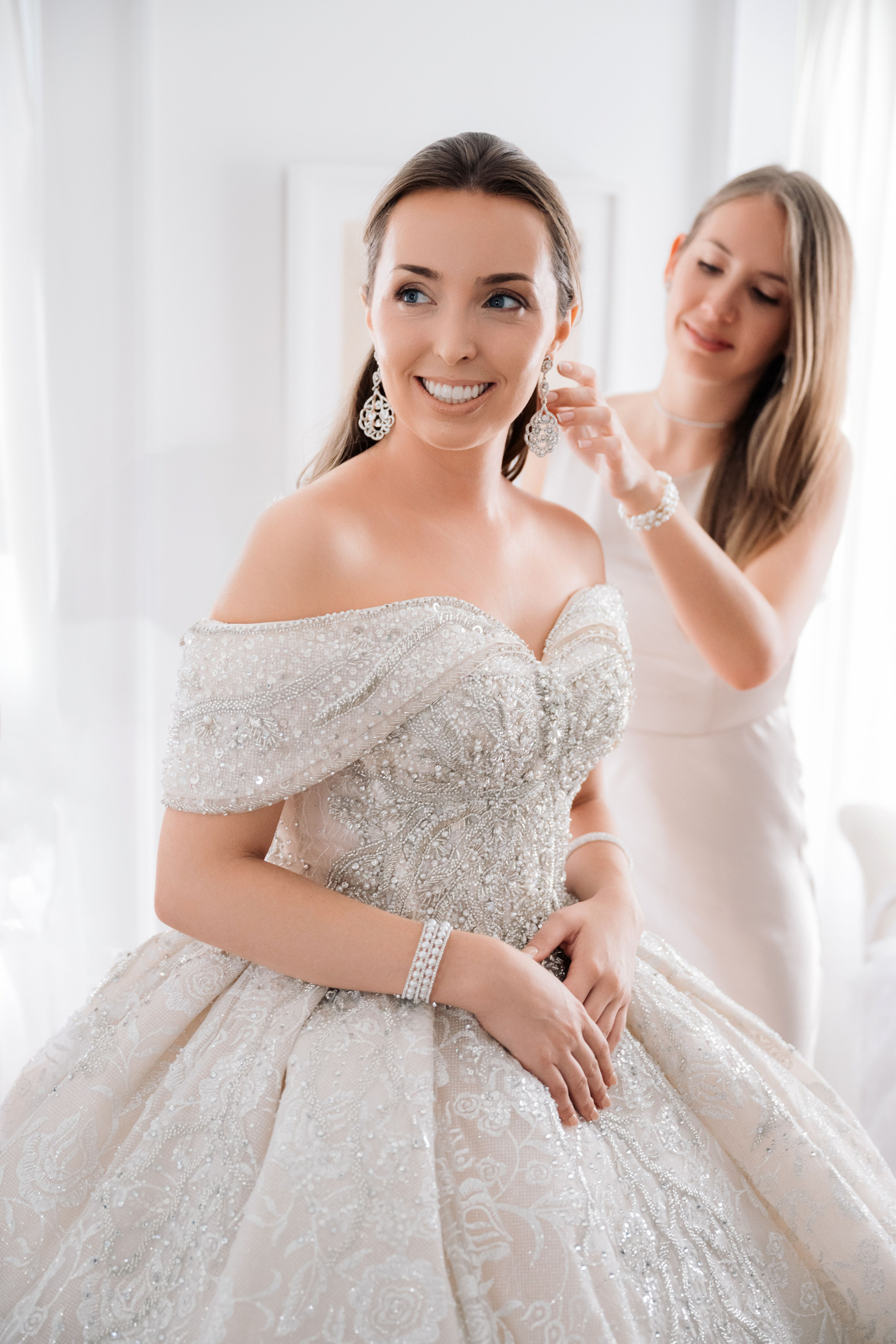 a woman in a wedding dress is putting her earrings