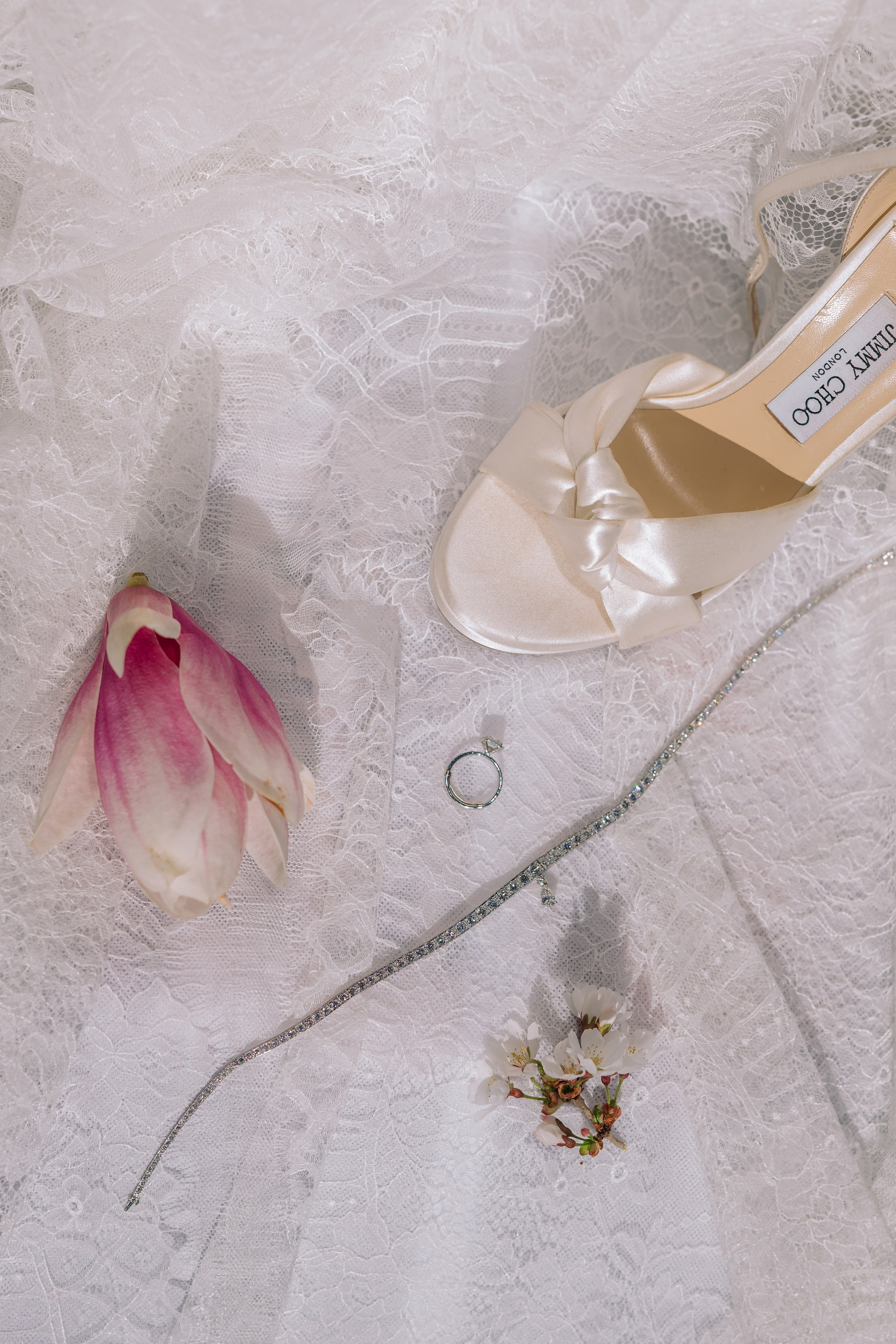 a pair of shoes and a flower on a white lace table cloth