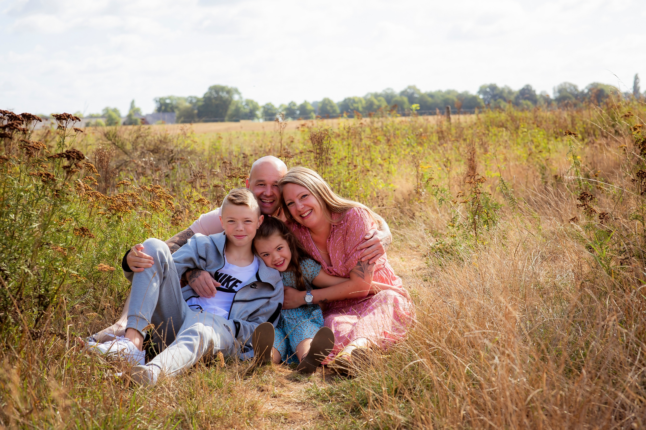 Gezin van vier personen samen zittend op het gras aan het knuffelen