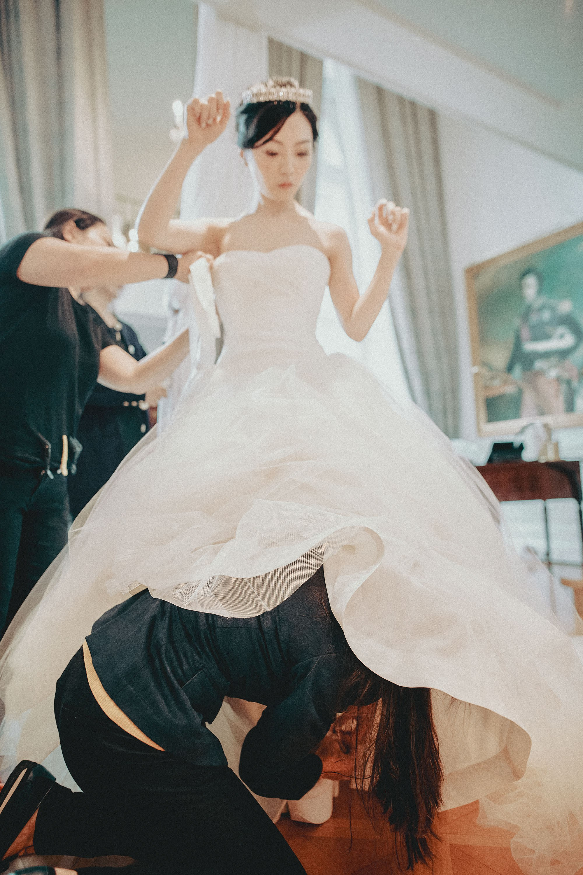 The bride is assisted by her staff into her wedding dress.
