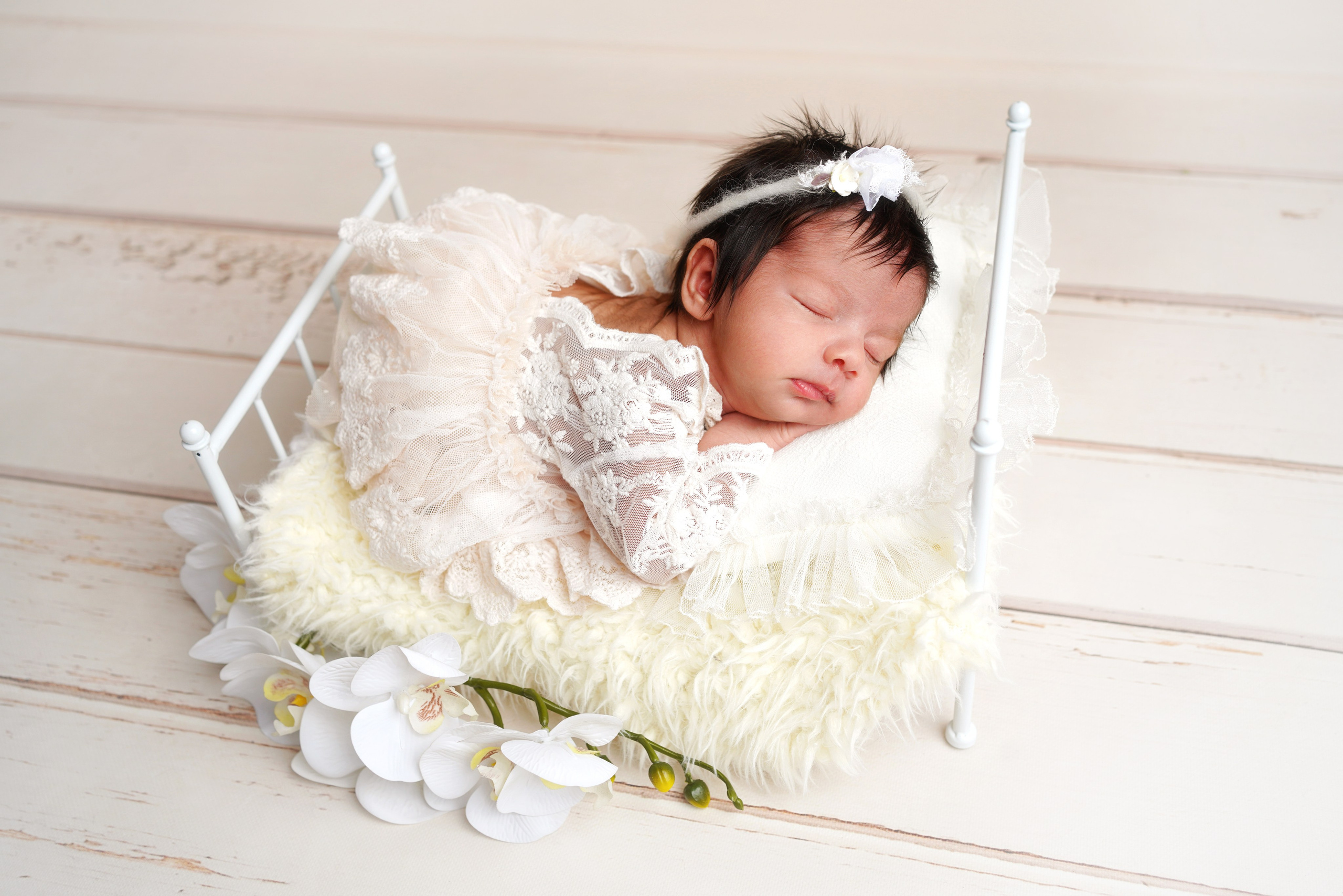 Schlafendes Baby, das in einem klassischen Babybett liegt, umgeben von Kuscheltieren