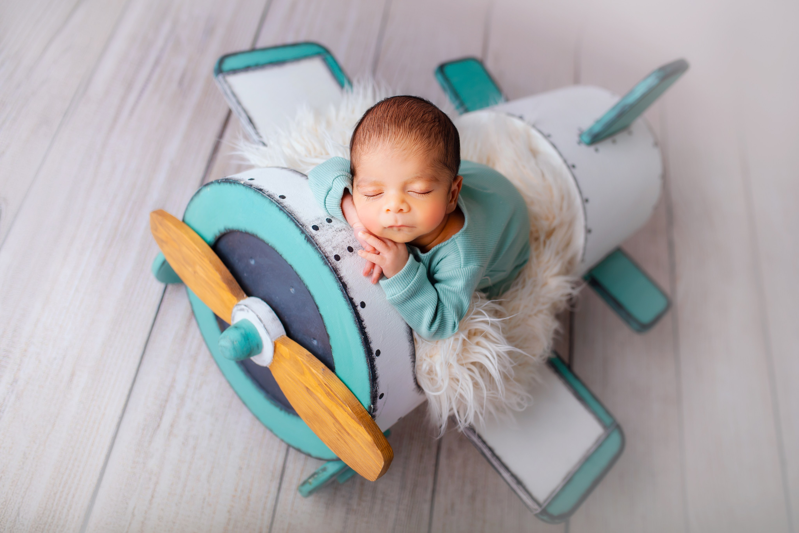 Sleeping newborn baby in an airplane prop during a professional newborn photography session
