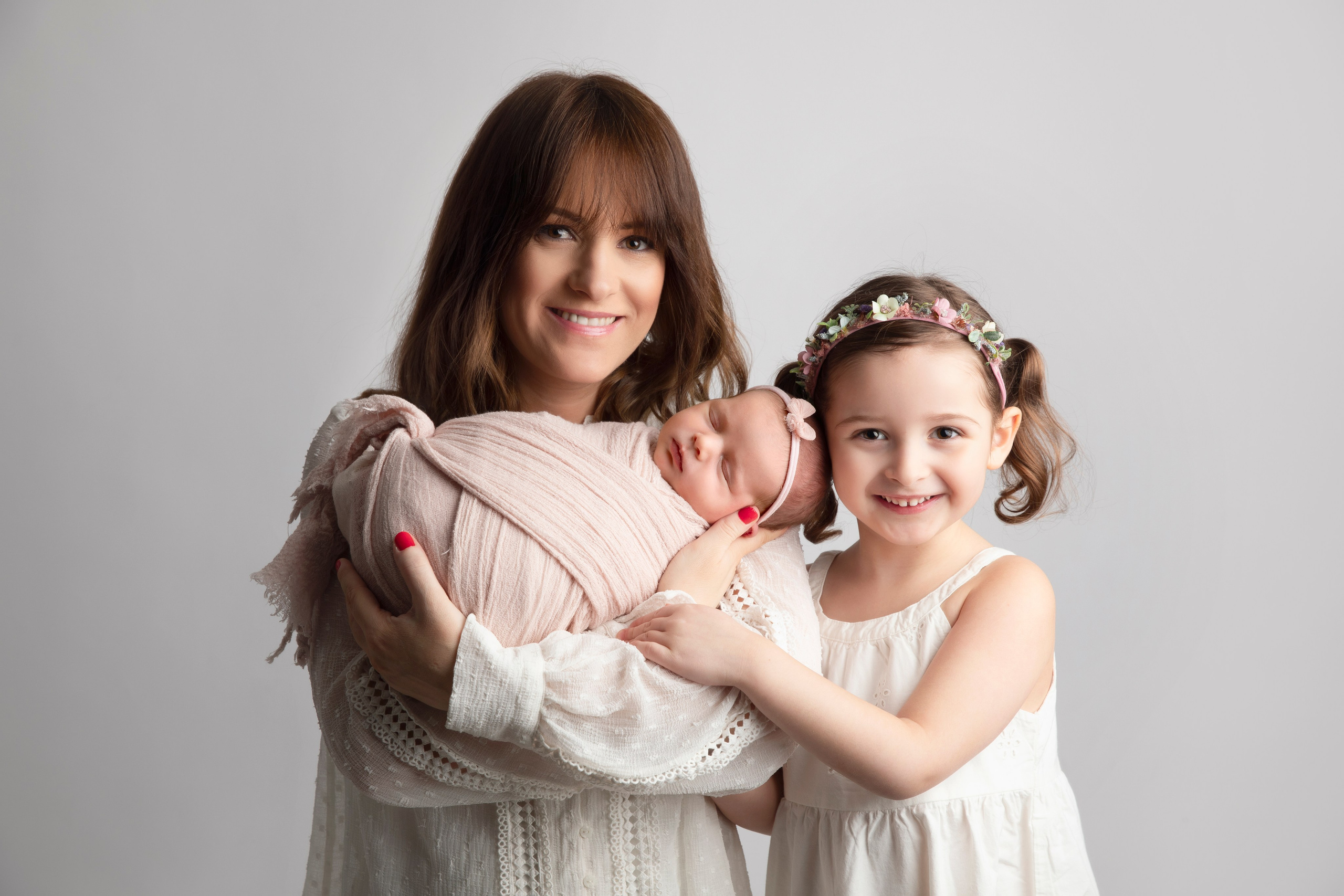 "Familjebild där föräldrarna sitter med sina nyfödda barn och äldre syskon. Bilden visar den ömma och kärleksfulla relationen mellan familjemedlemmarna och den nya tillskottet till familjen."