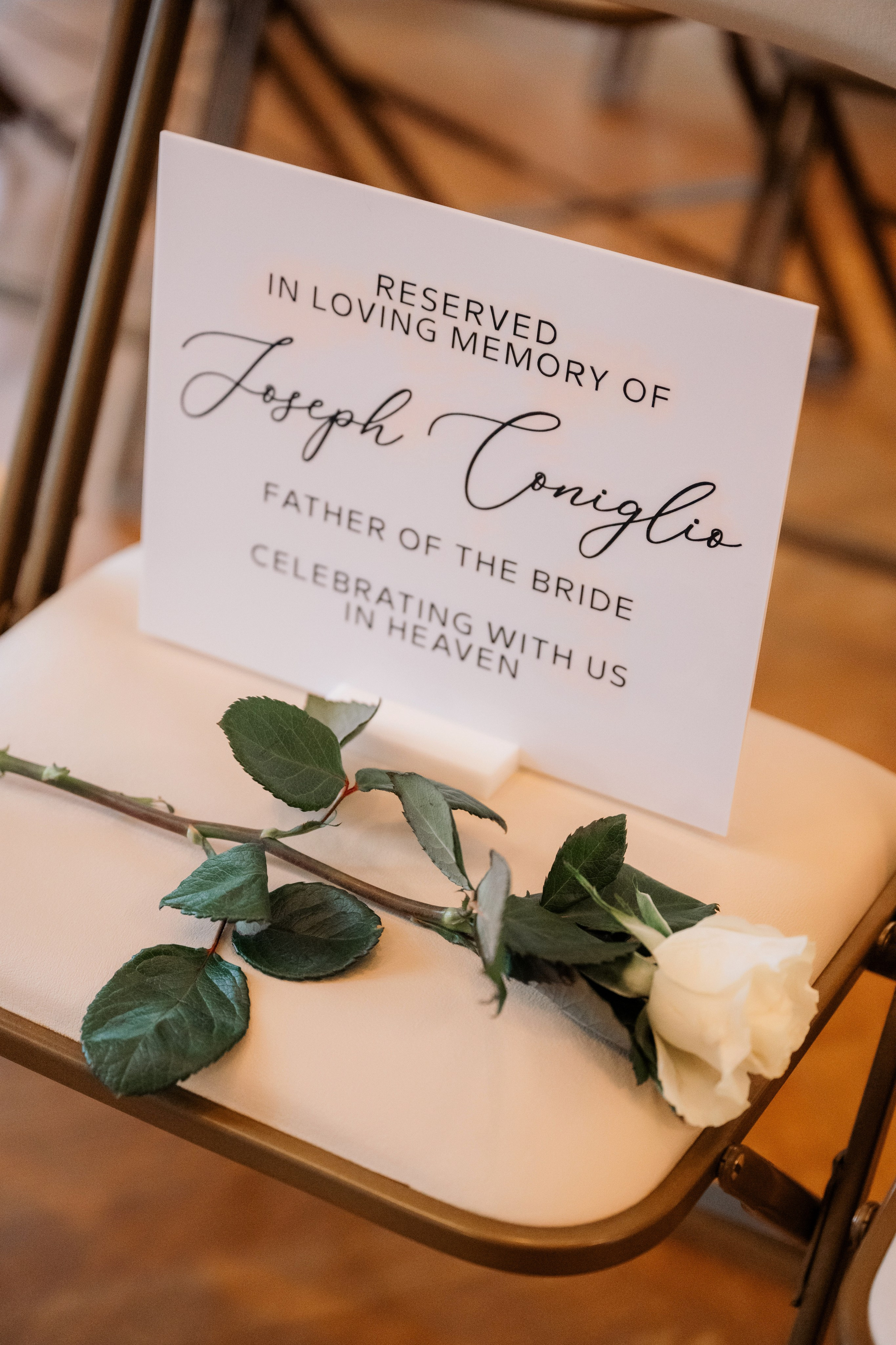 a white rose sits on a chair with a sign