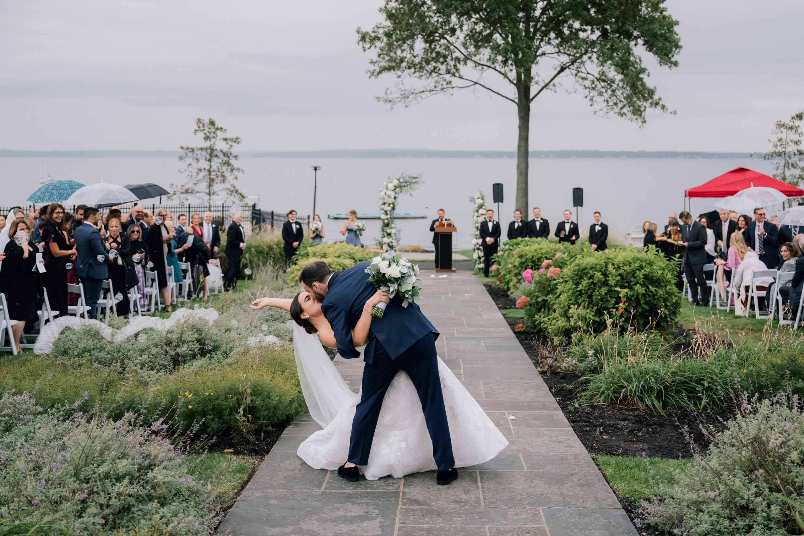 a bride and groom kiss in front of a wedding party