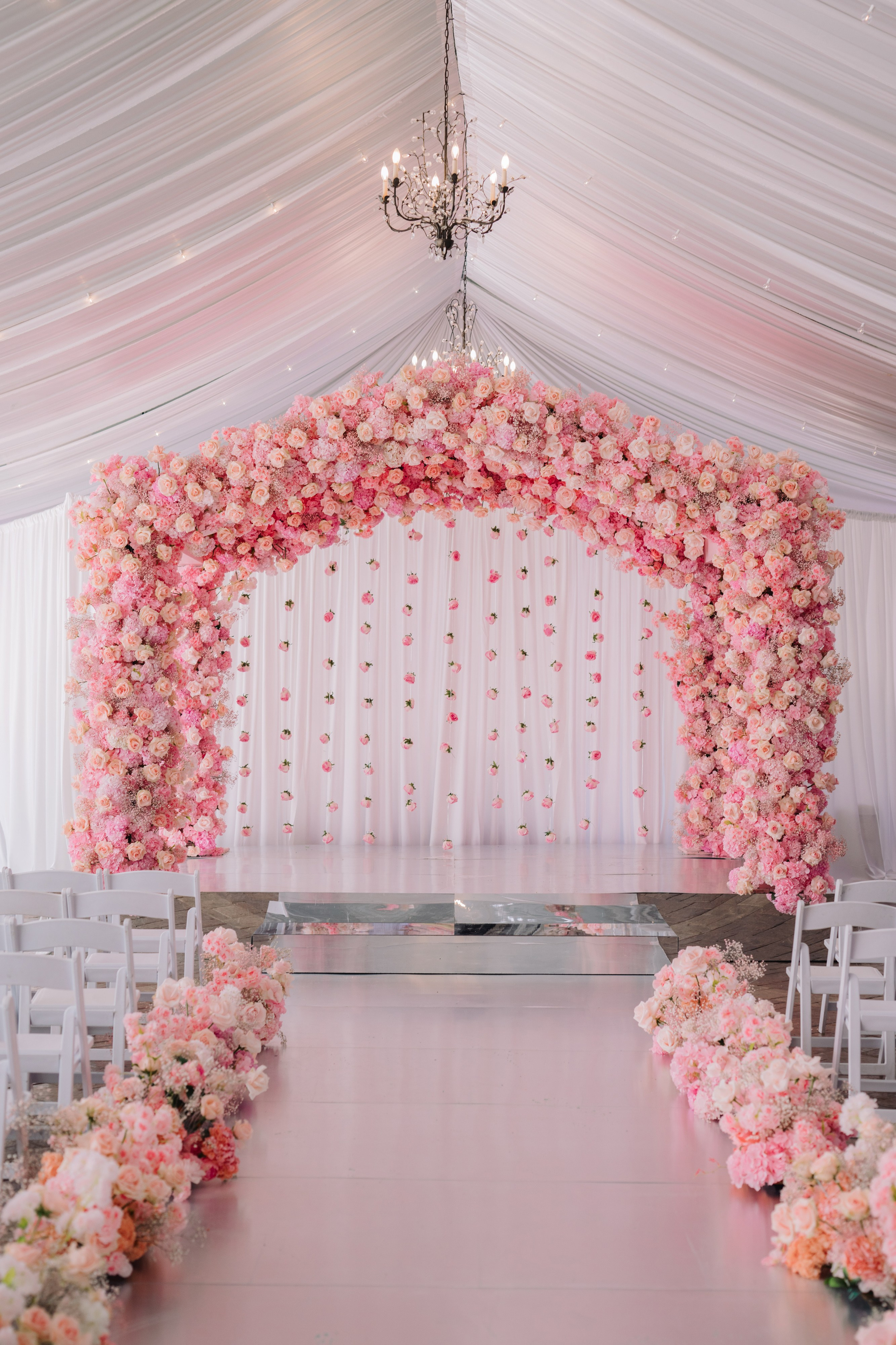 a wedding ceremony with pink flowers and white chairs