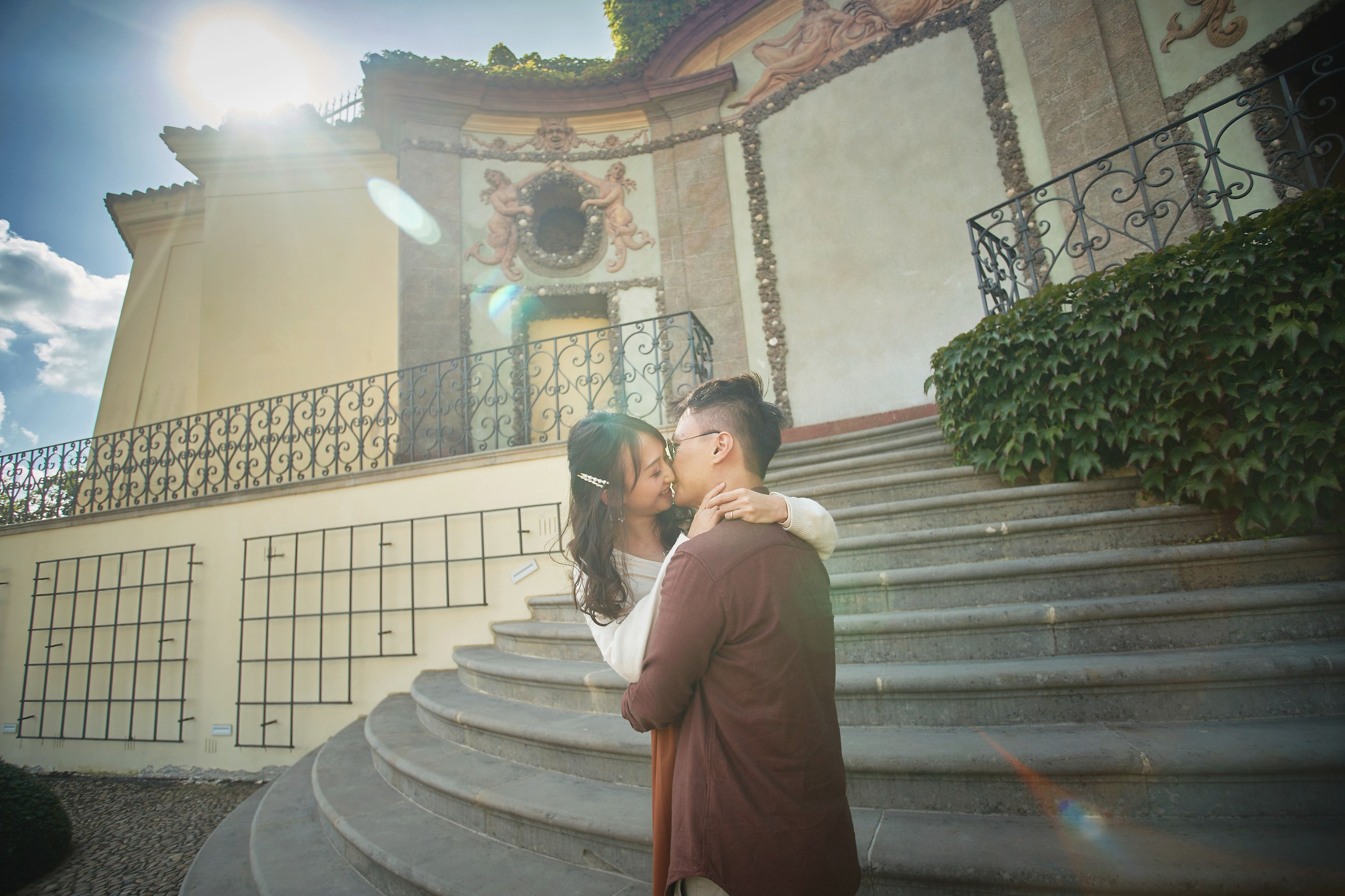 Eva and Conan embracing with lens flare near the top of Vrtba Garden, Prague.
