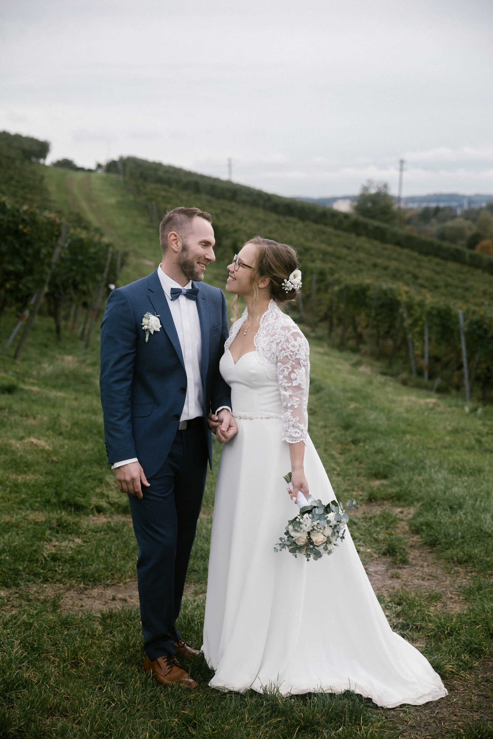 Hochzeitspaar blickt sich verliebt in den Markdorfer Weinbergen an