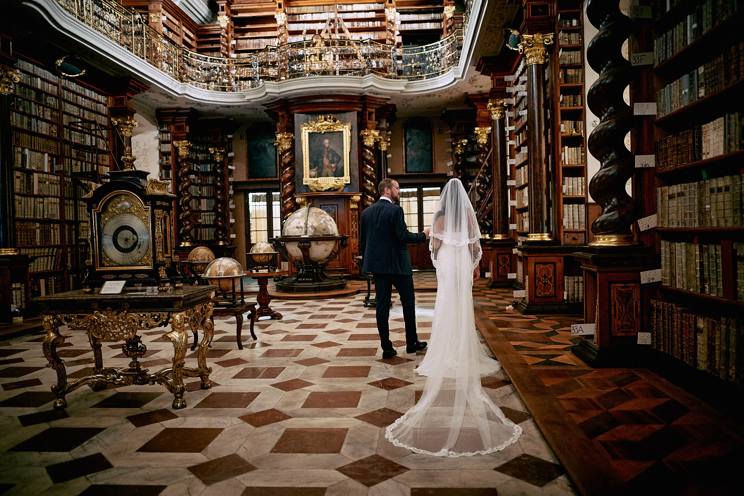 Couple marveling at opulent interiors of historic Klementinum Astronomical Tower Library.