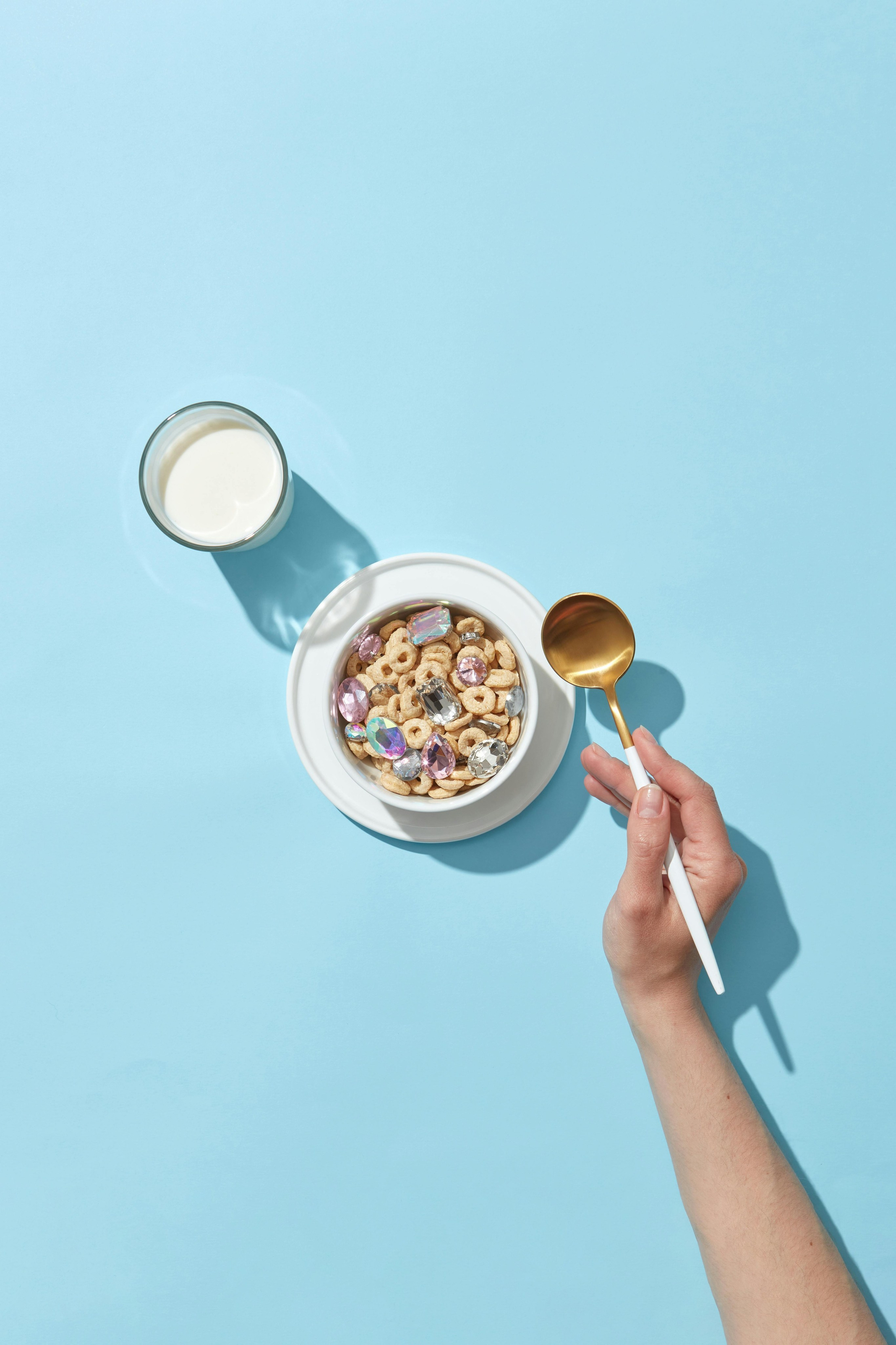 Modern lifestyle food photo of hand holding cereal bowl on pastel blue background, photographed by Jay Soundo.