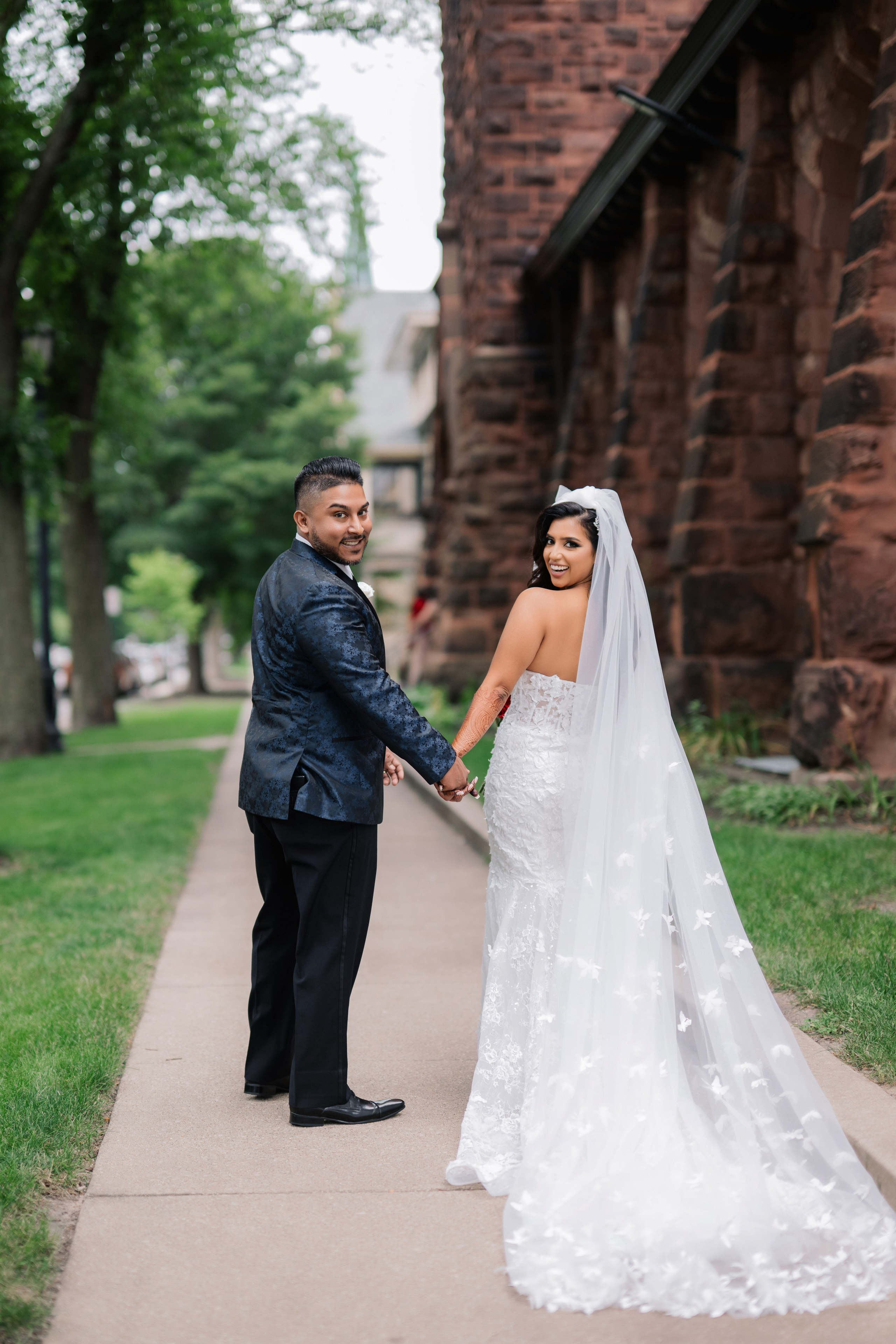 a bride and groom standing on a sidewalk