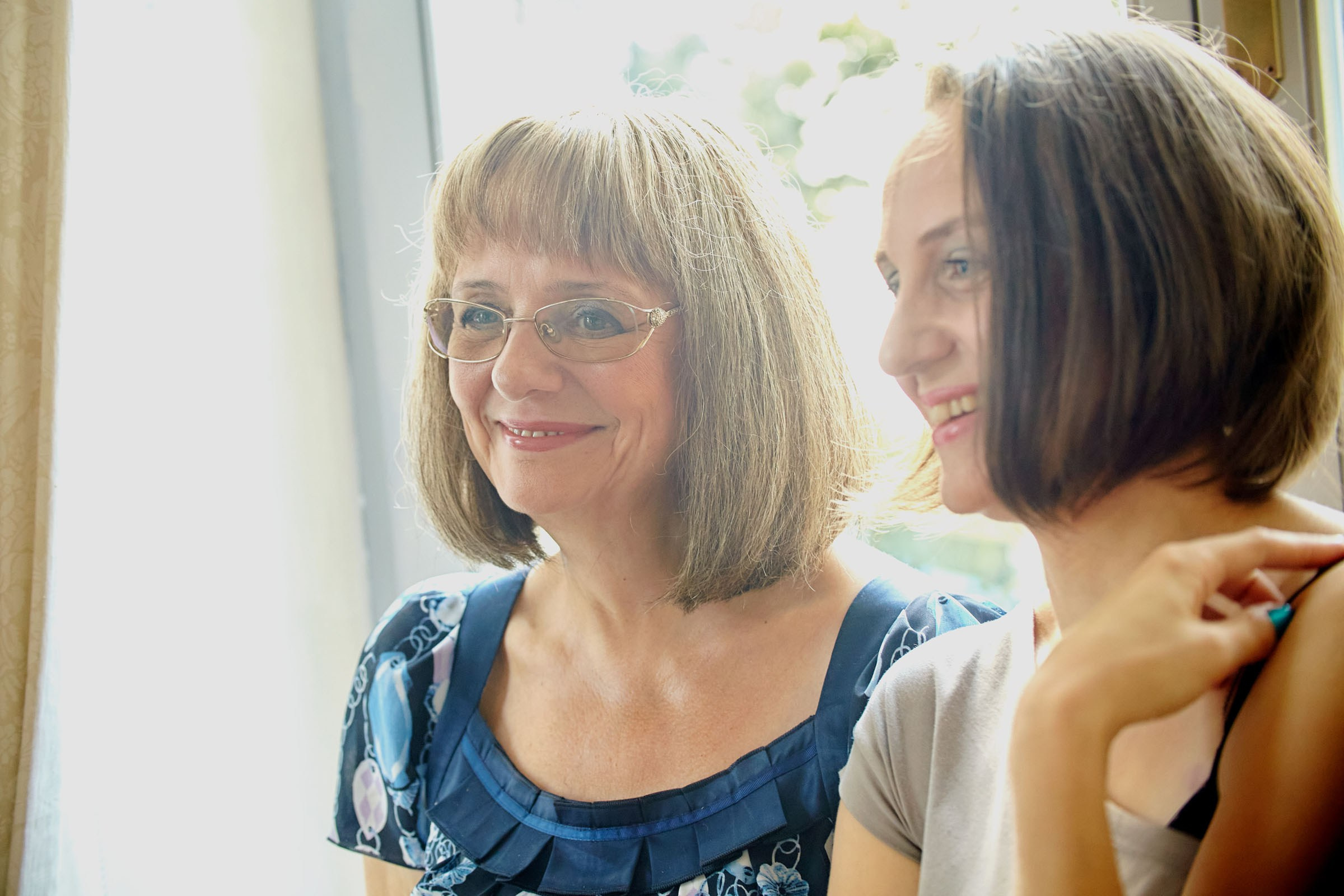 Mother of the bride and her aunt observing the bridal prep with smiles.