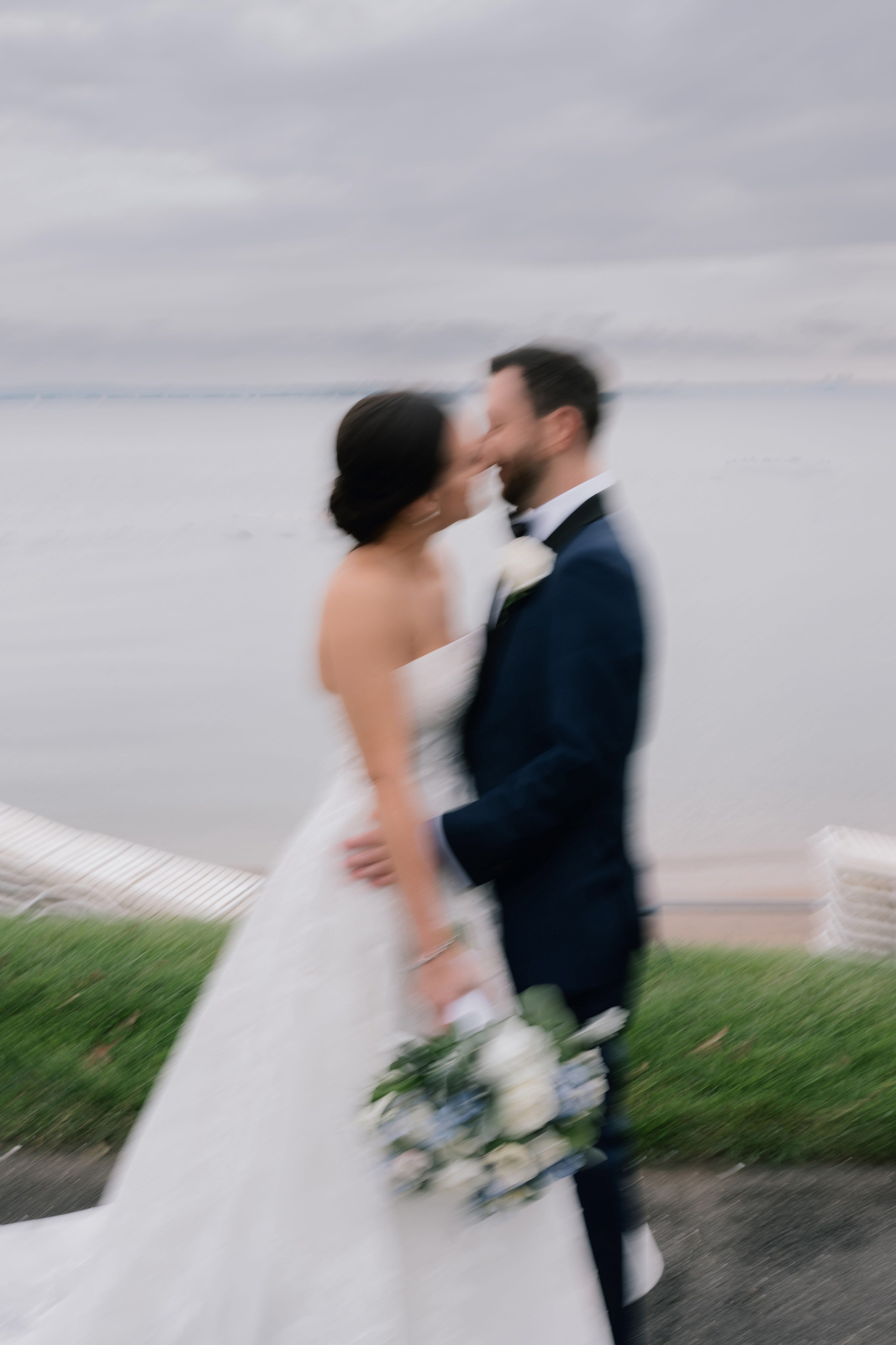 a bride and groom kissing on a path by the water