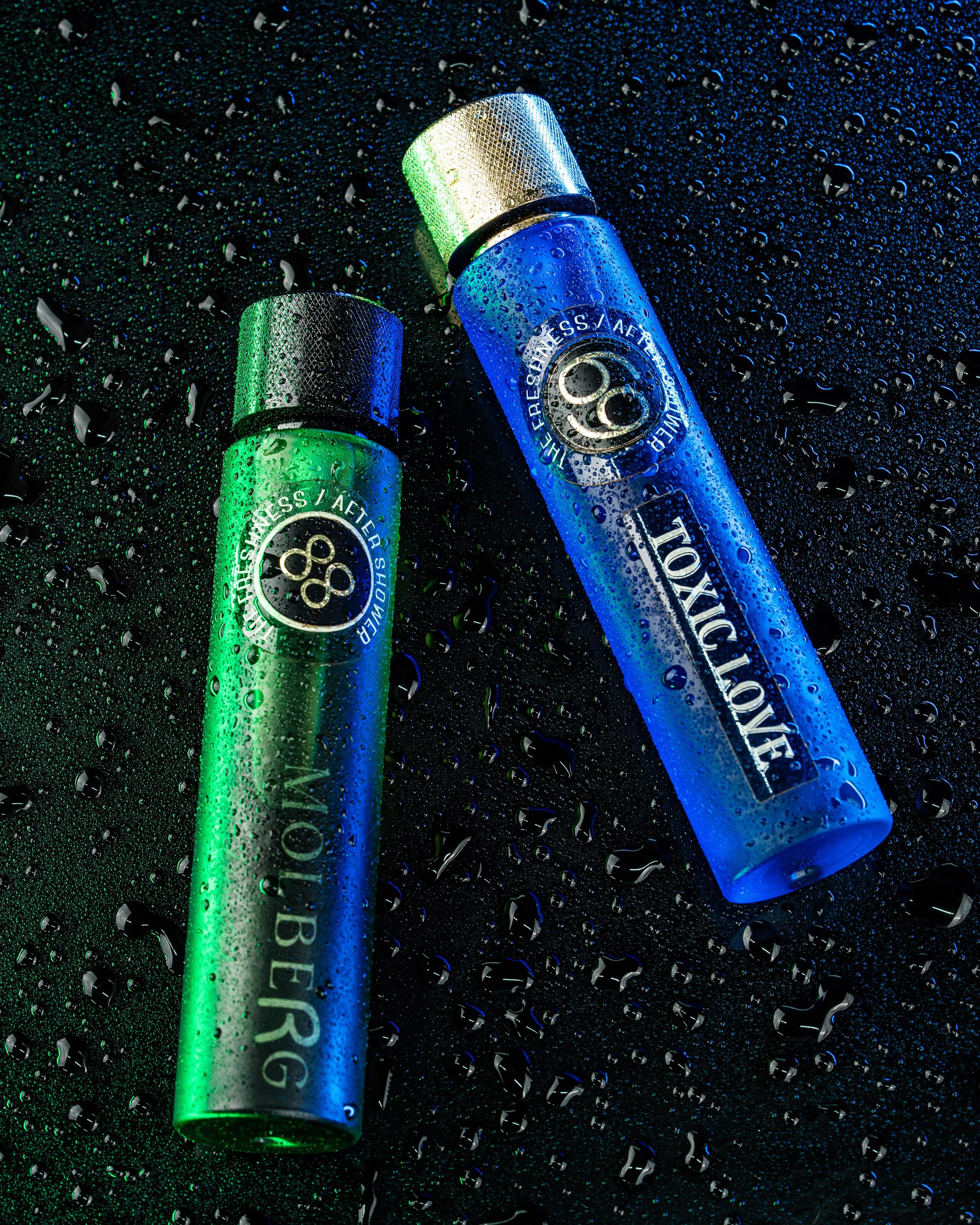 İki silindrik ətir və ya afterşave şüşəsi (biri yaşıl – "MOLBERG", digəri mavi – "TOXIC LOVE") su damcıları ilə örtülmüş parlaq qara səth üzərində təsvir edilmişdir. Şüşələr və arxa fon kontrast təşkil edən neon yaşıl və mavi işıqlarla dramatik şəkildə işıqlandırılmışdır ki, bu da şəklə canlı, yüksək kontrastlı və nəm bir görünüş verir.