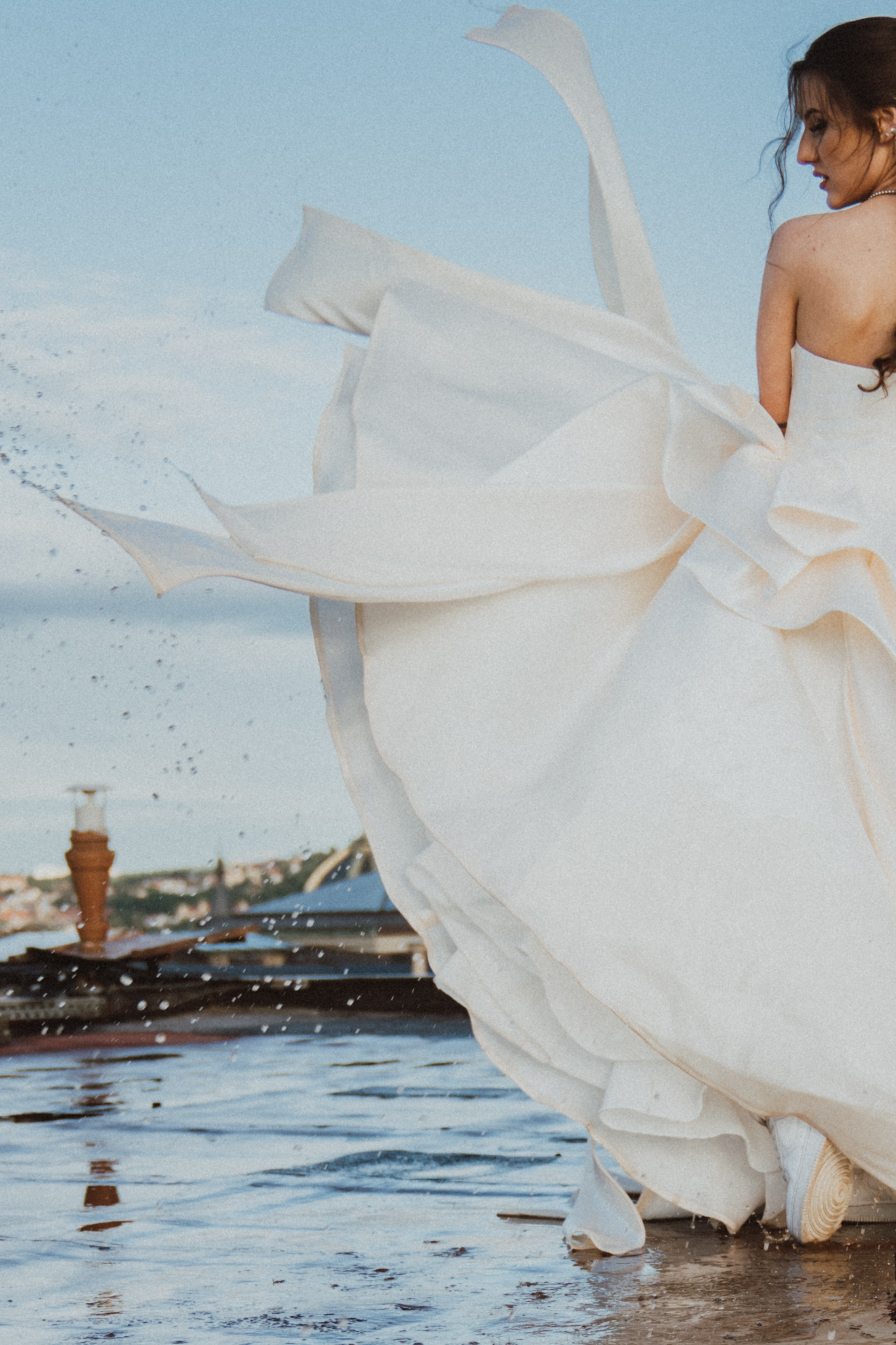 Nevěsta s mokrými svatebními šaty během svatby ve dvou v Praze, kapky vody stříkají z látky při pohybu.