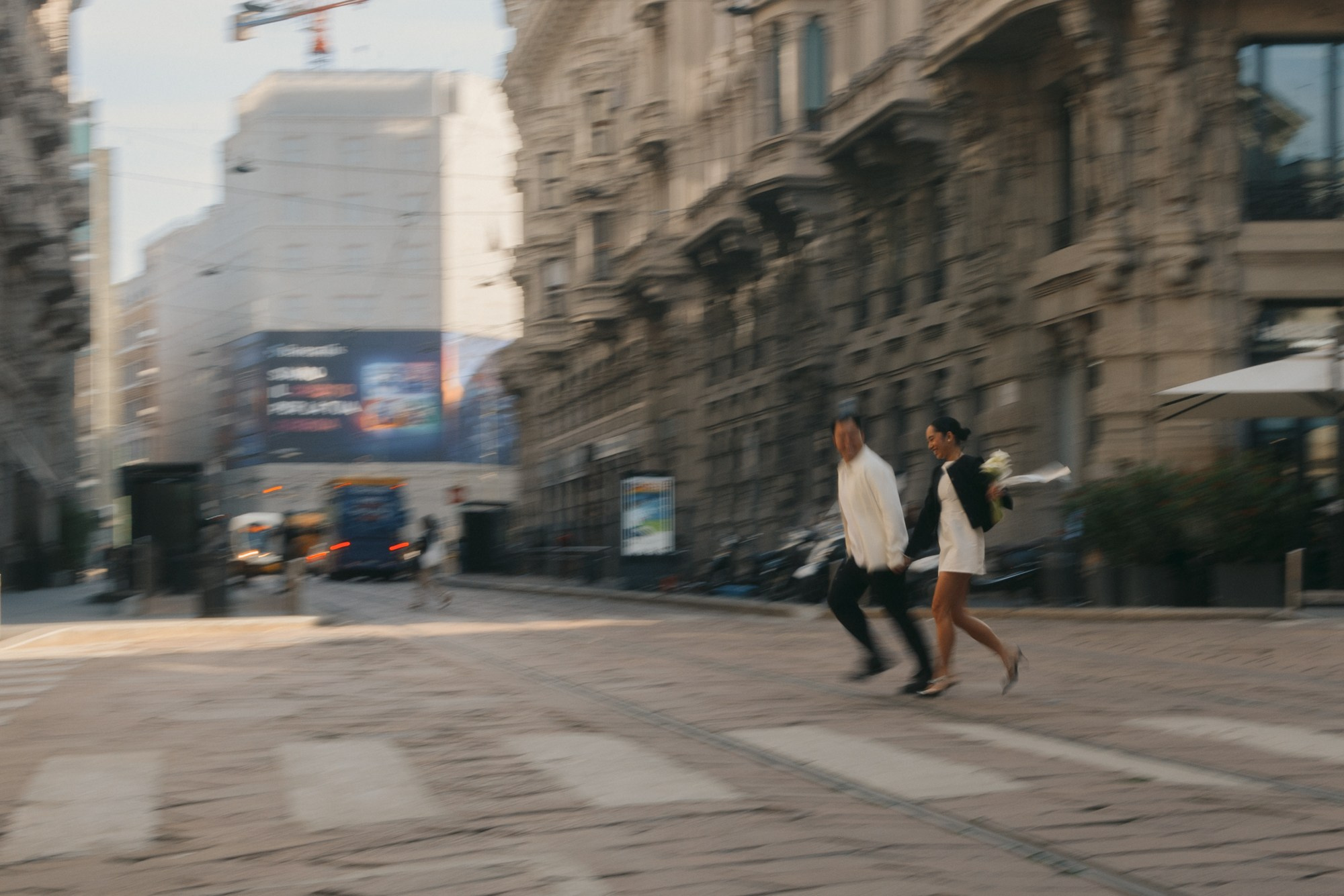 Dynamic and emotional shot of newlyweds running hand in hand through the historic streets of Milan. A spontaneous moment full of joy and movement that captures the authentic energy and romance of a modern wedding love story. Milan wedding photographer, Milan couple photoshoot, Milan love story, wedding photography Milan, couple in Milan, elopement Milan, romantic couple photos