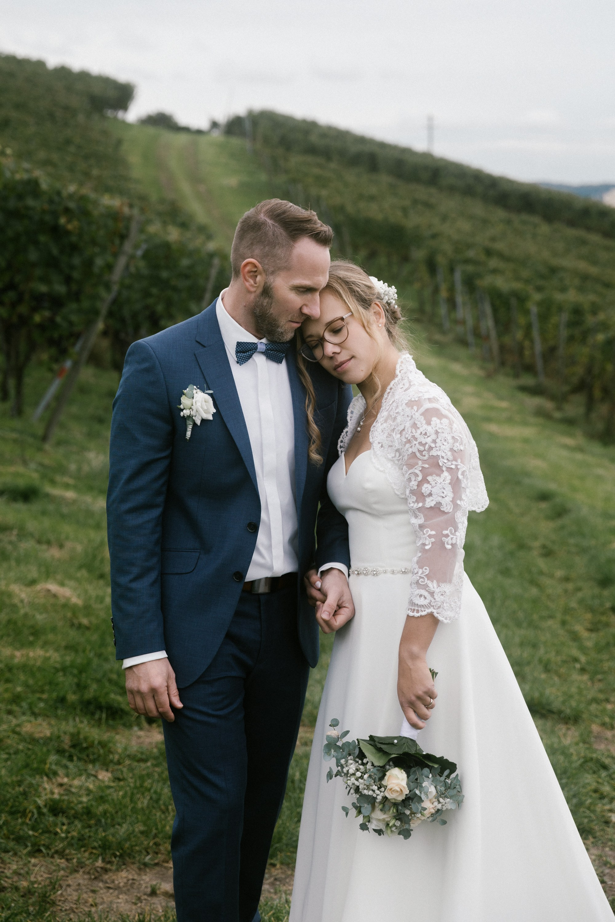 Braut legt zärtlich den Kopf an Bräutigam im Weinberg Markdorf