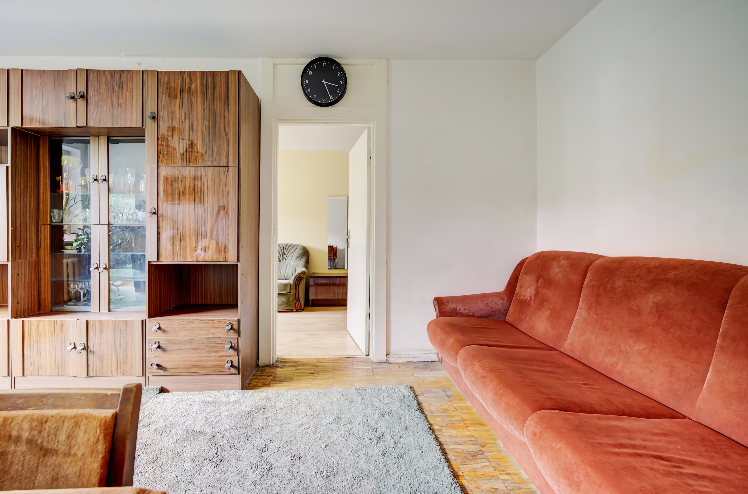 Svetainės ir valgomojo zona su raudona sofa, krištoliniu sietynu ir paveikslais ant sienų.