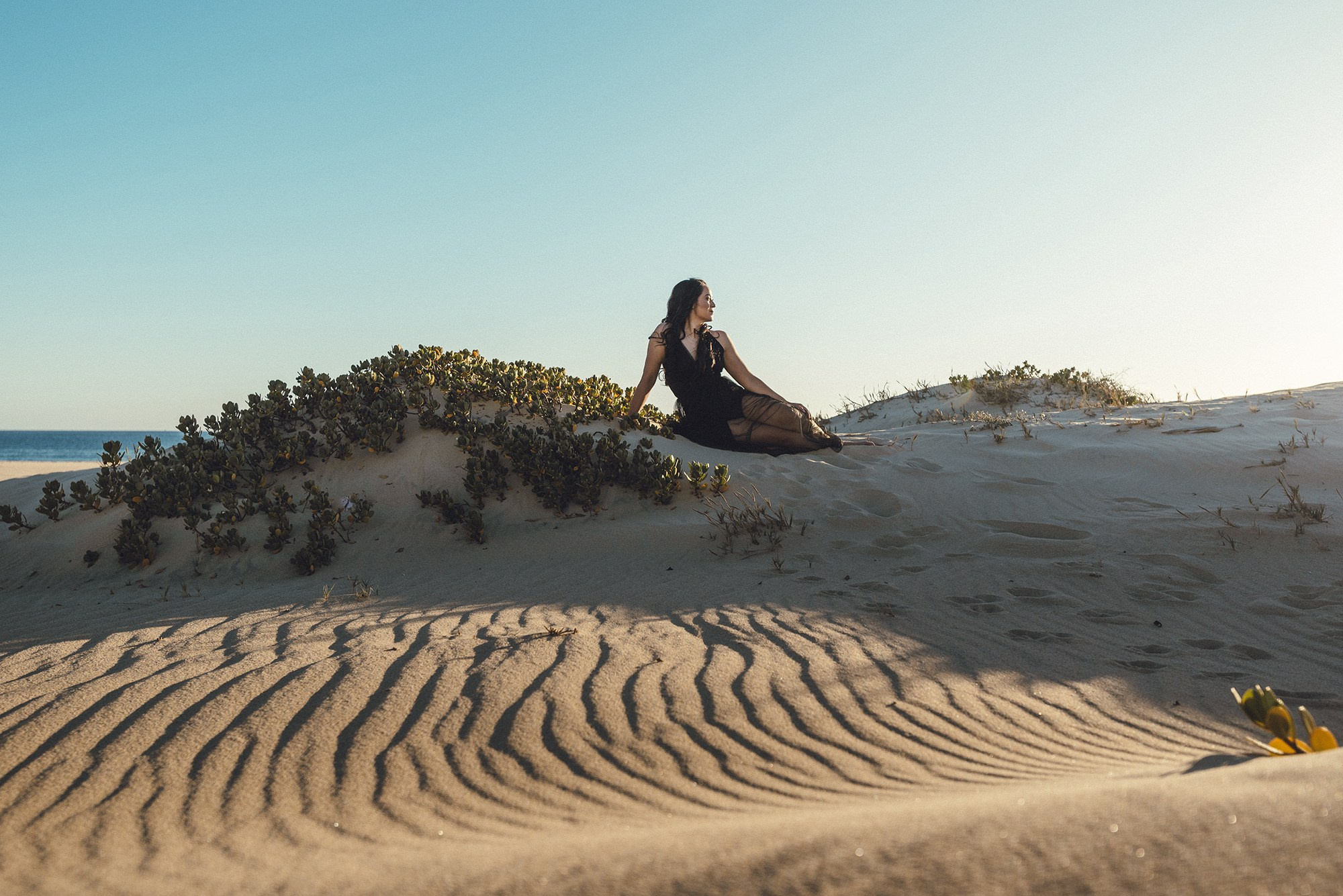 Woman sitting on sand dunes during lifestyle portrait session in Los Cabos, Baja California Sur