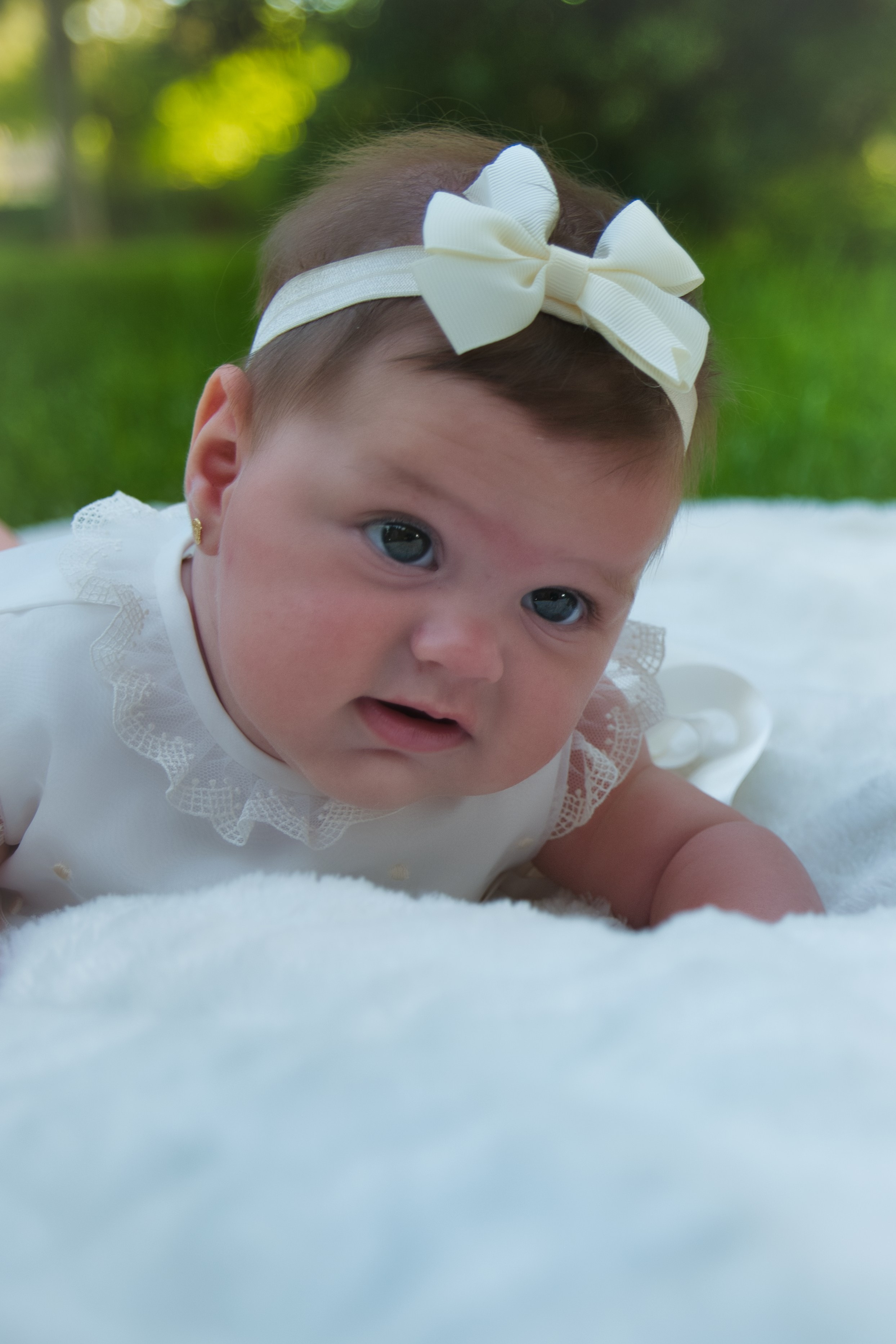 Niña vestida con traje de bautizo blanco, sostenida por sus padres en la iglesia.
