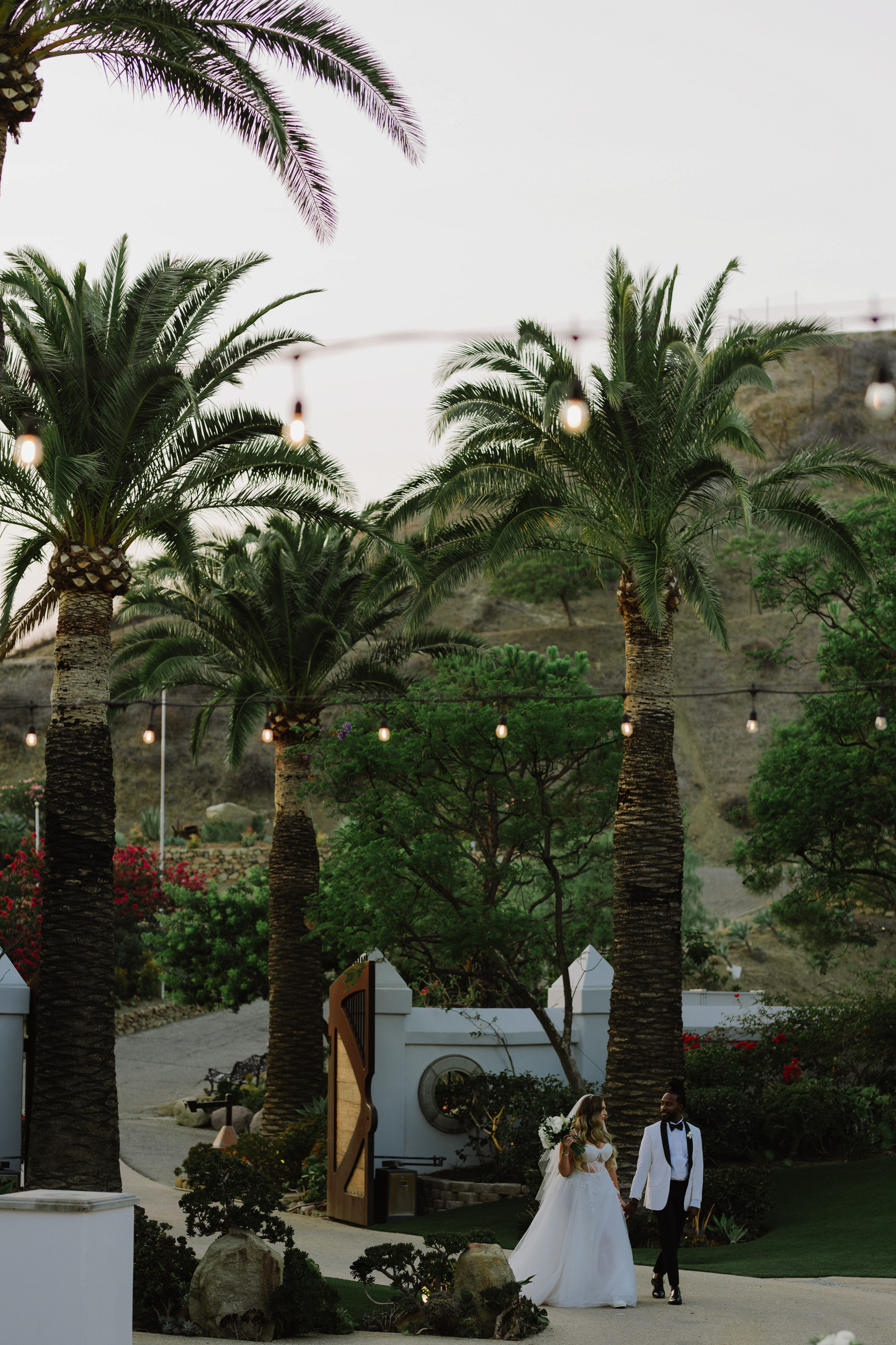 a couple is walking down the aisle with palm trees