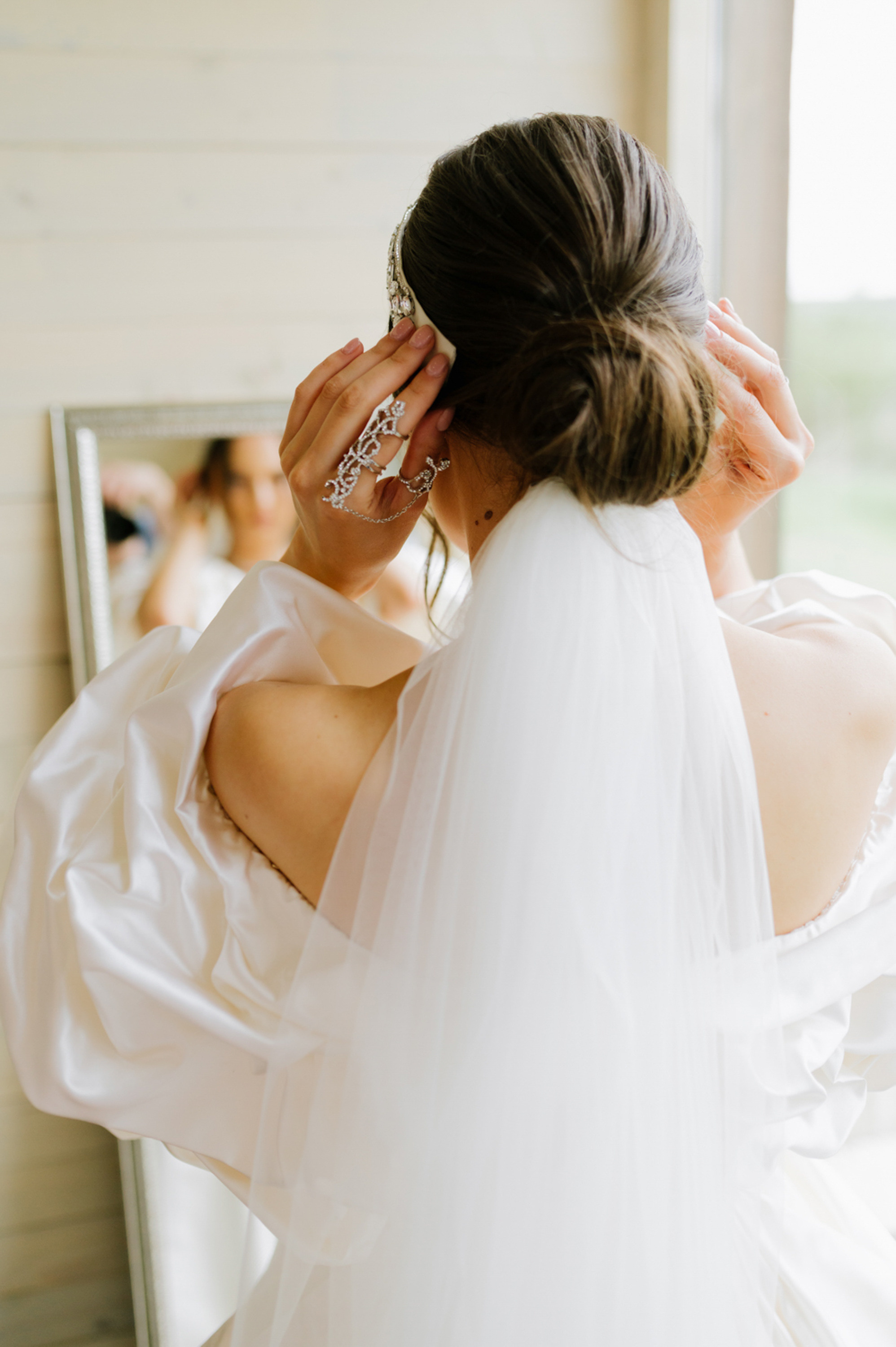 a bride putting her hair in front of a mirror