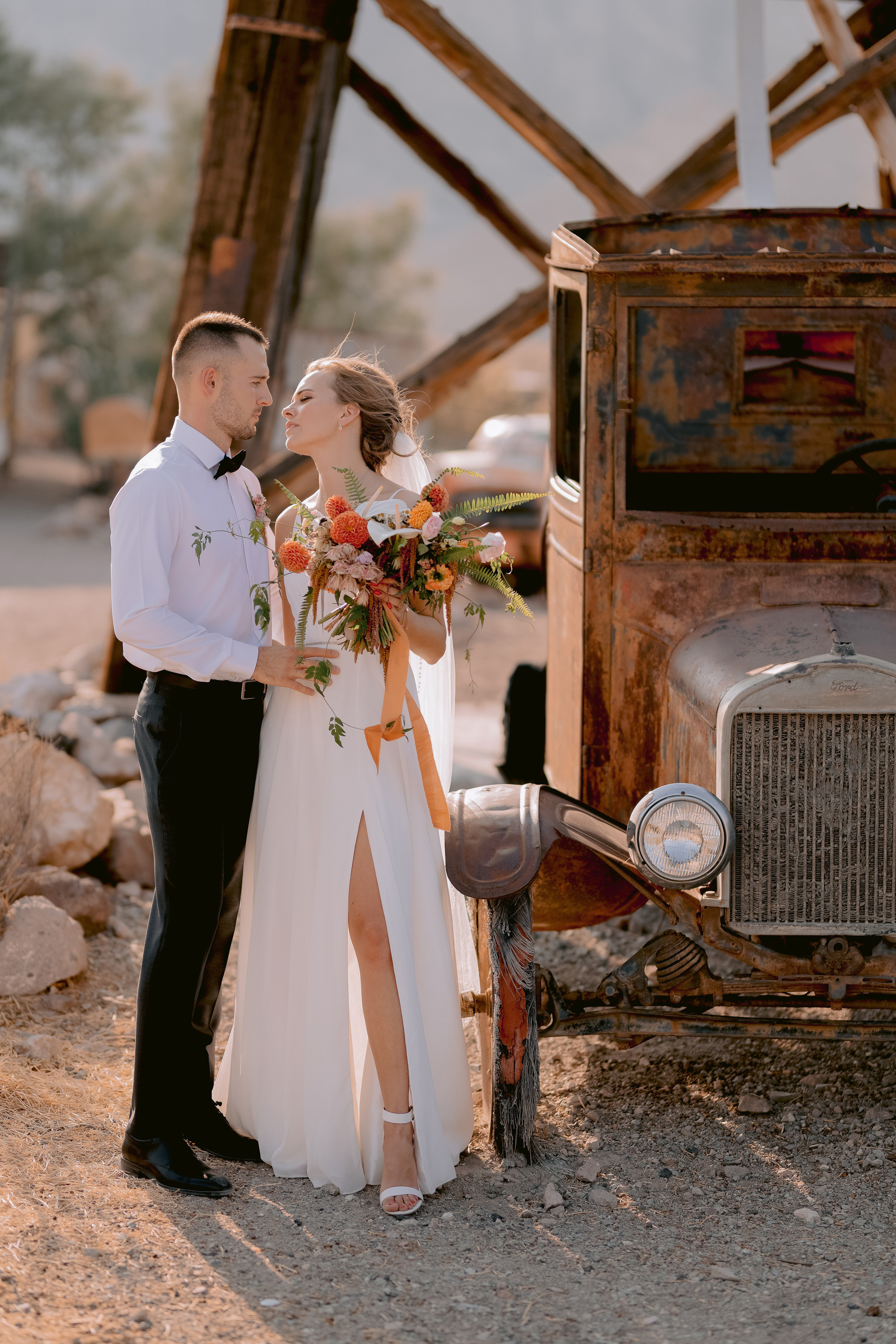 a bride and groom kissing in front of an old truck