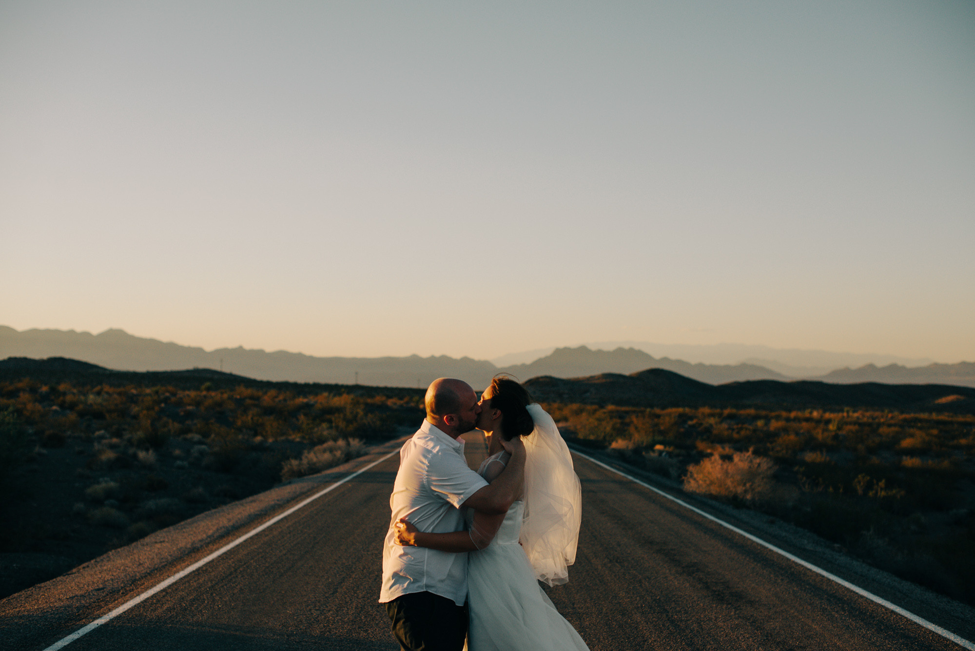 a bride and groom kissing on a road