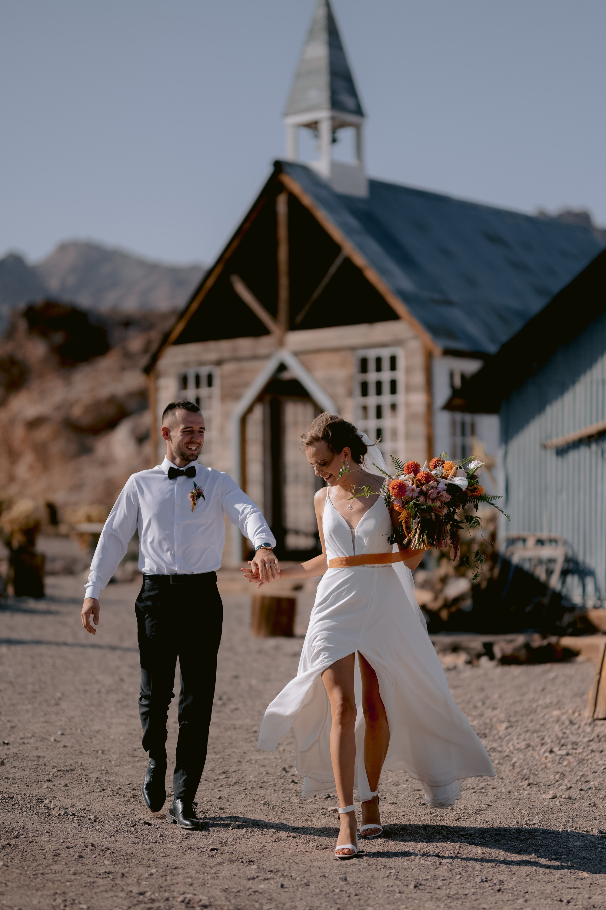 a bride and groom walking in the dirt