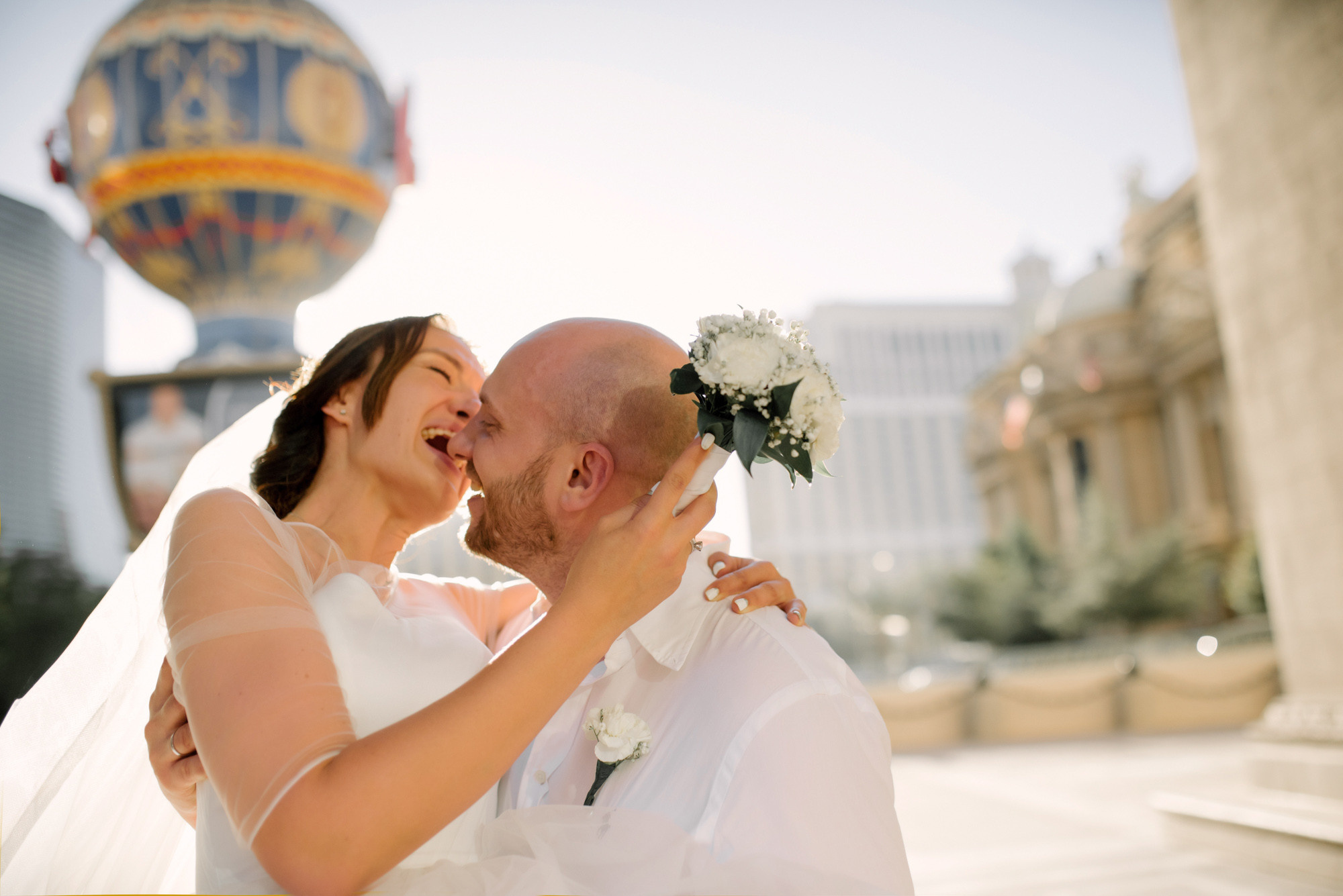 a bride and groom kissing in front of a hot air balloon