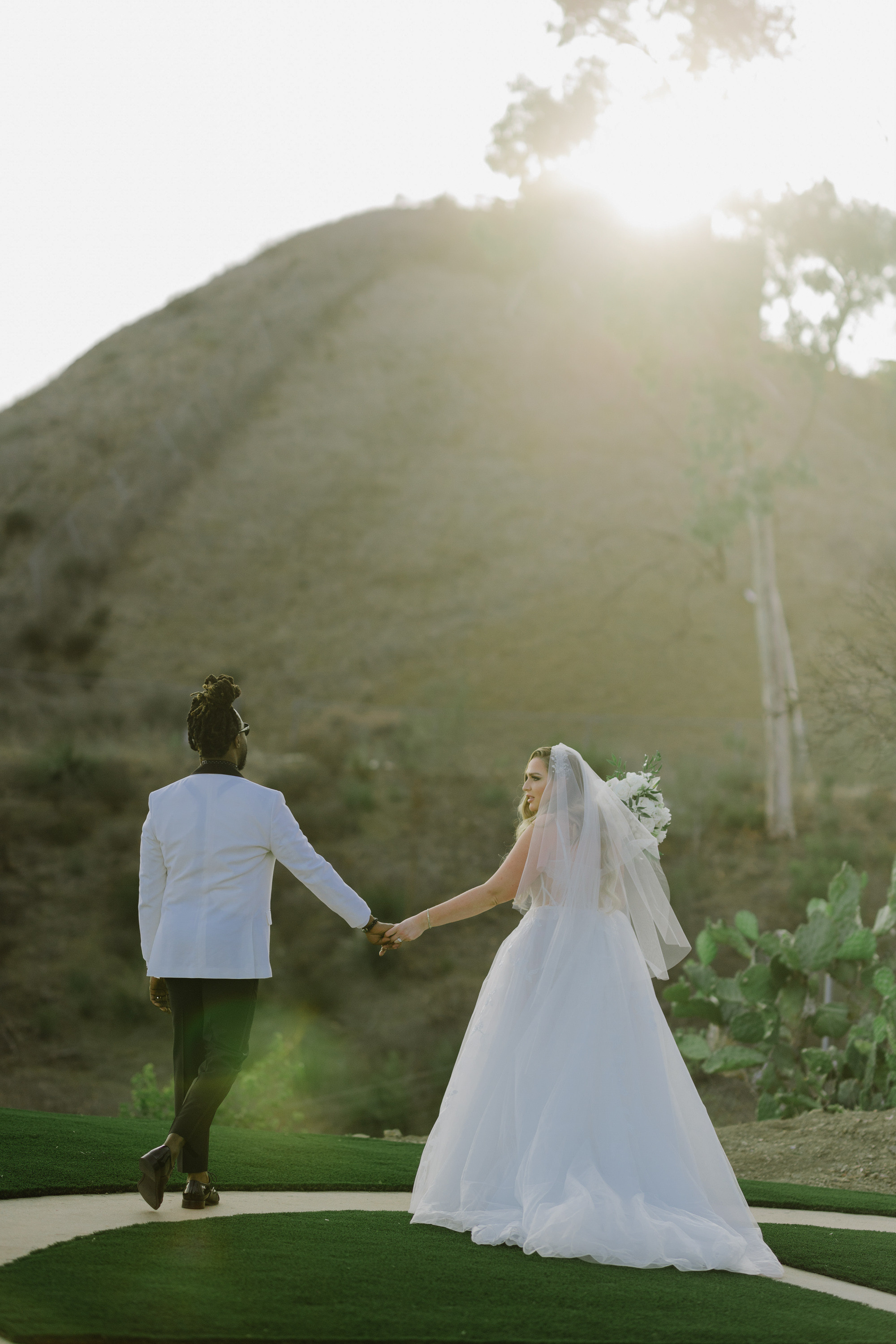 a bride and groom walking on a path