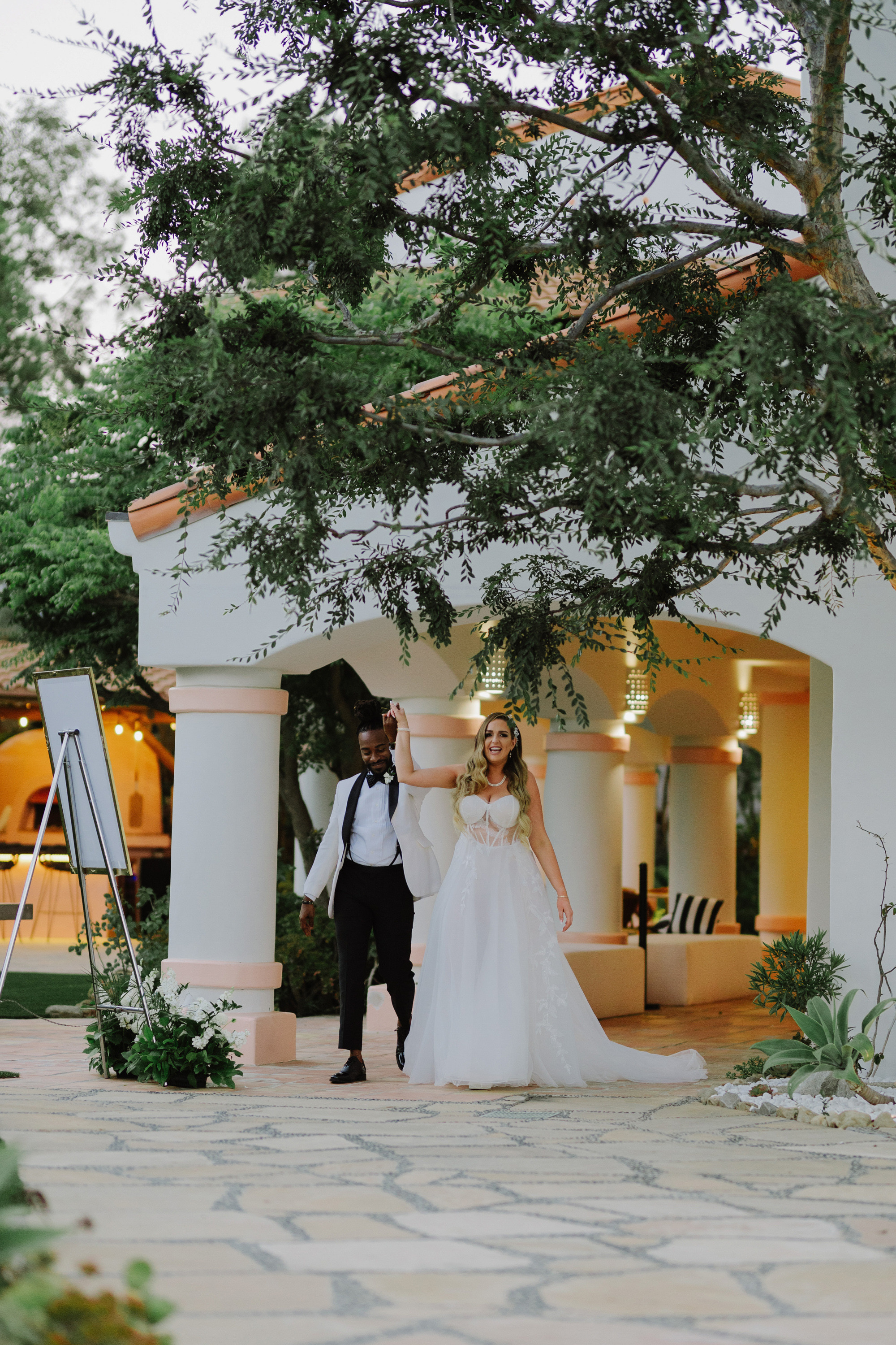 a bride and groom walking through a courtyard