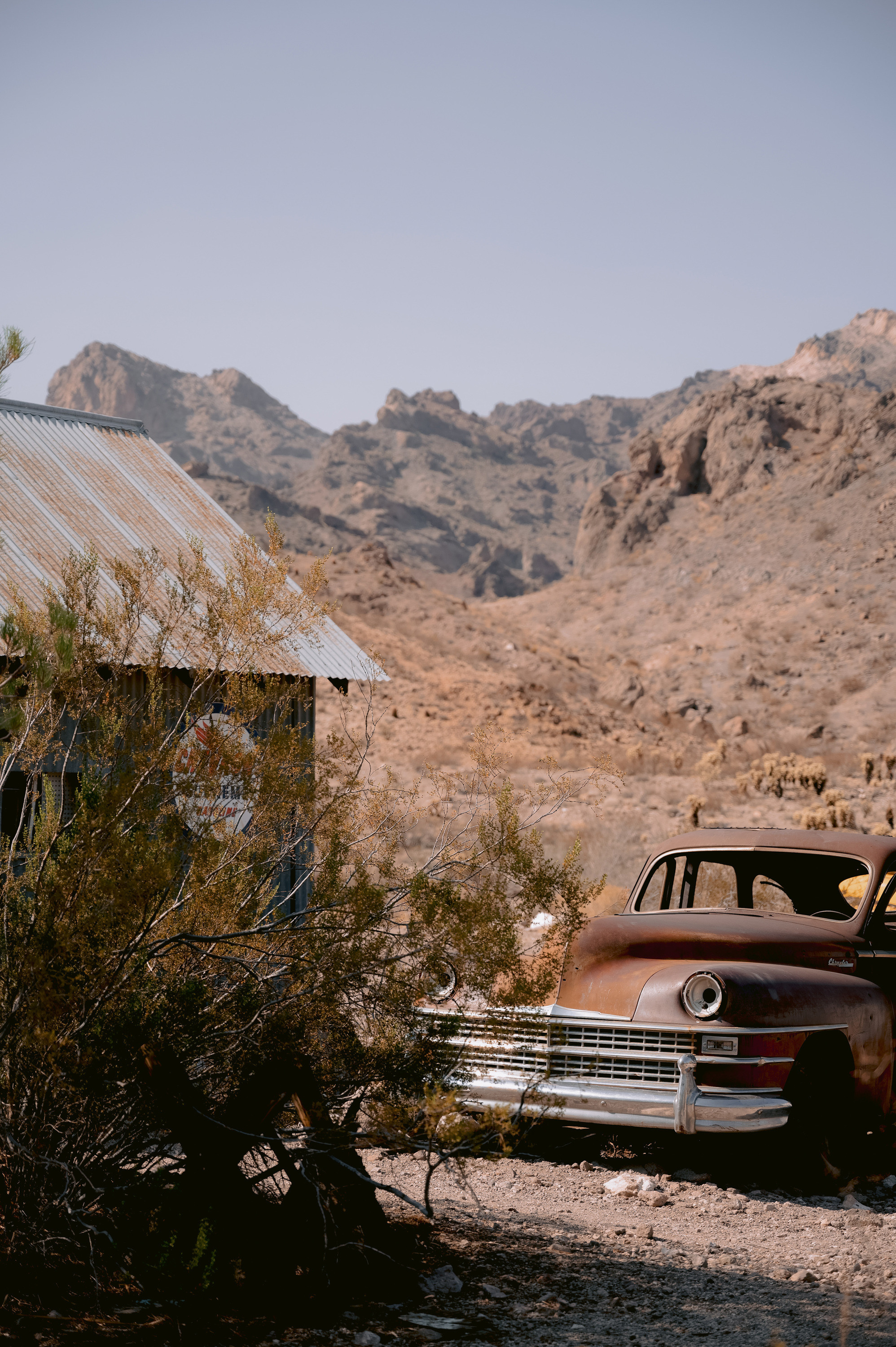 a rusted old car sits in a desert