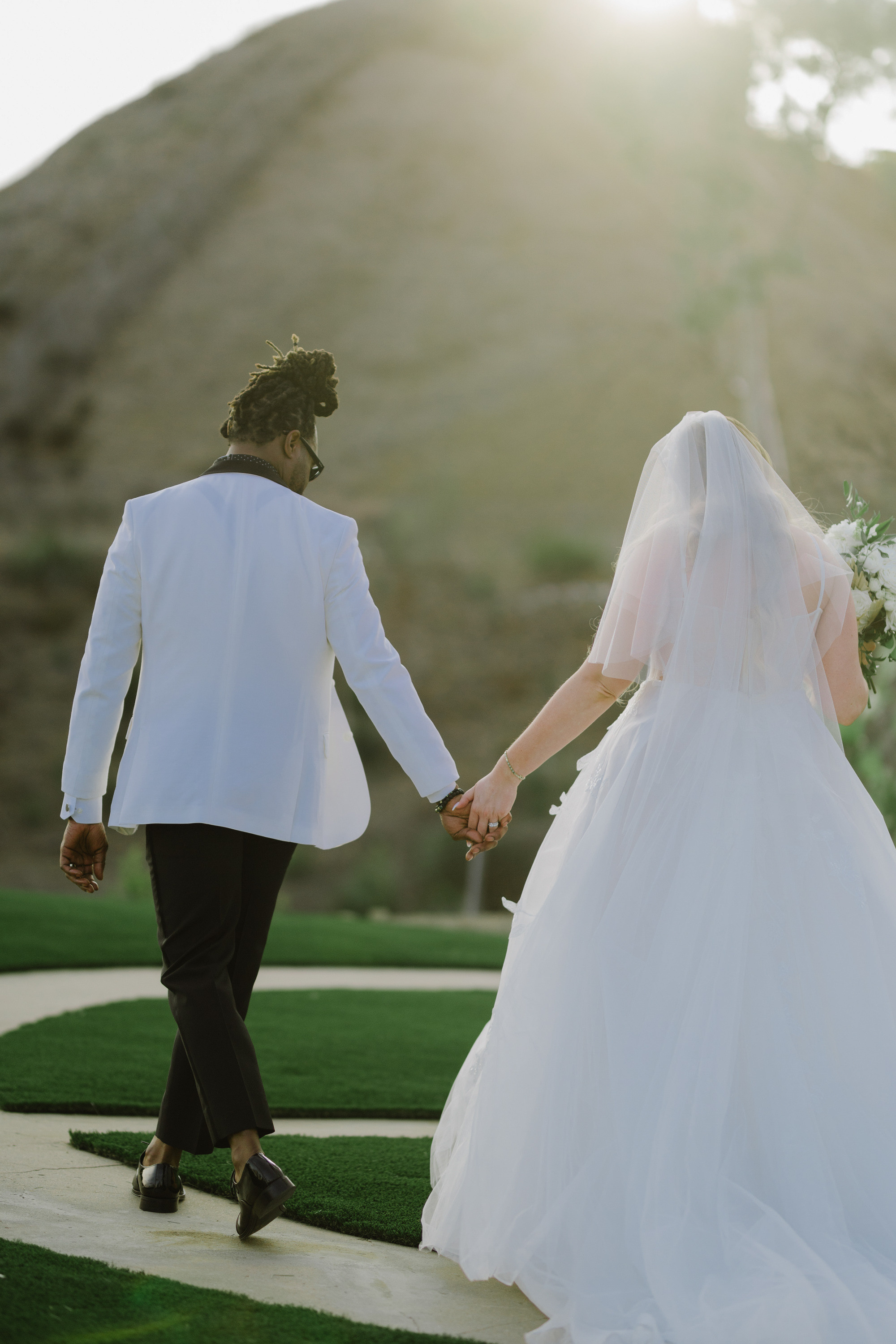 a bride and groom walking down a path