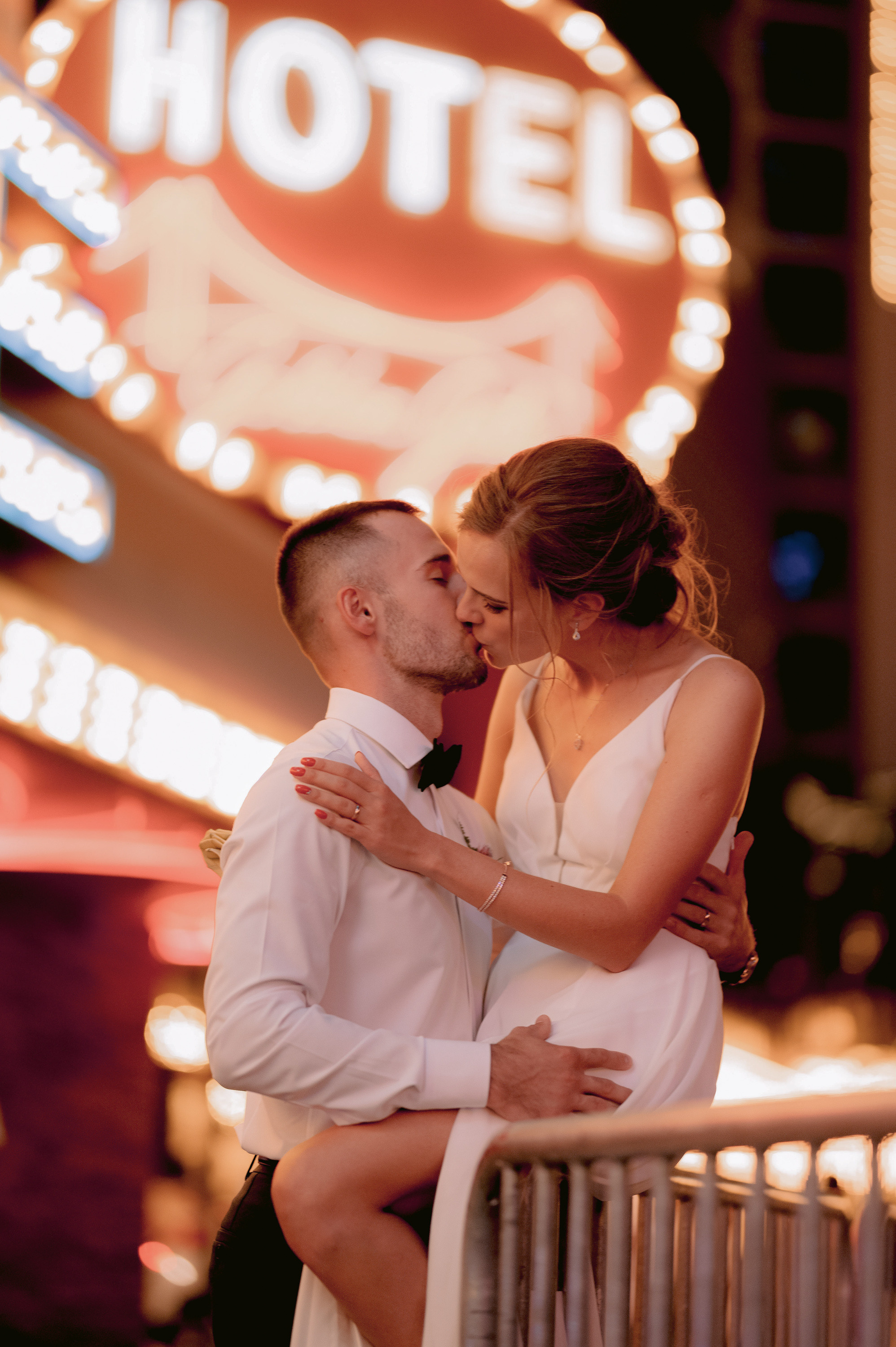 a couple kissing in front of a hotel sign