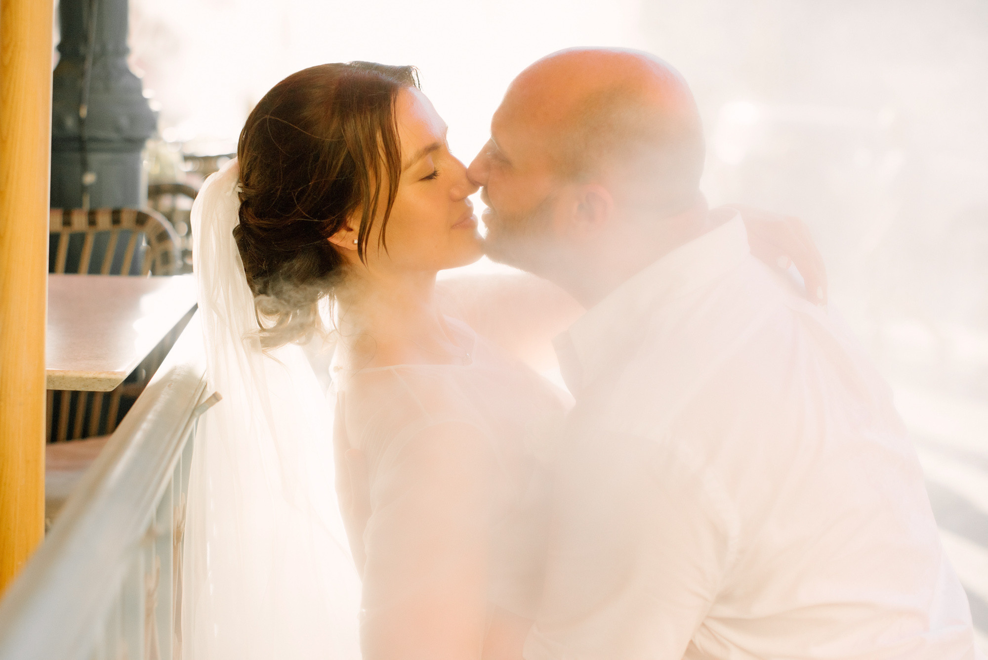 a bride and groom kissing on a balcony