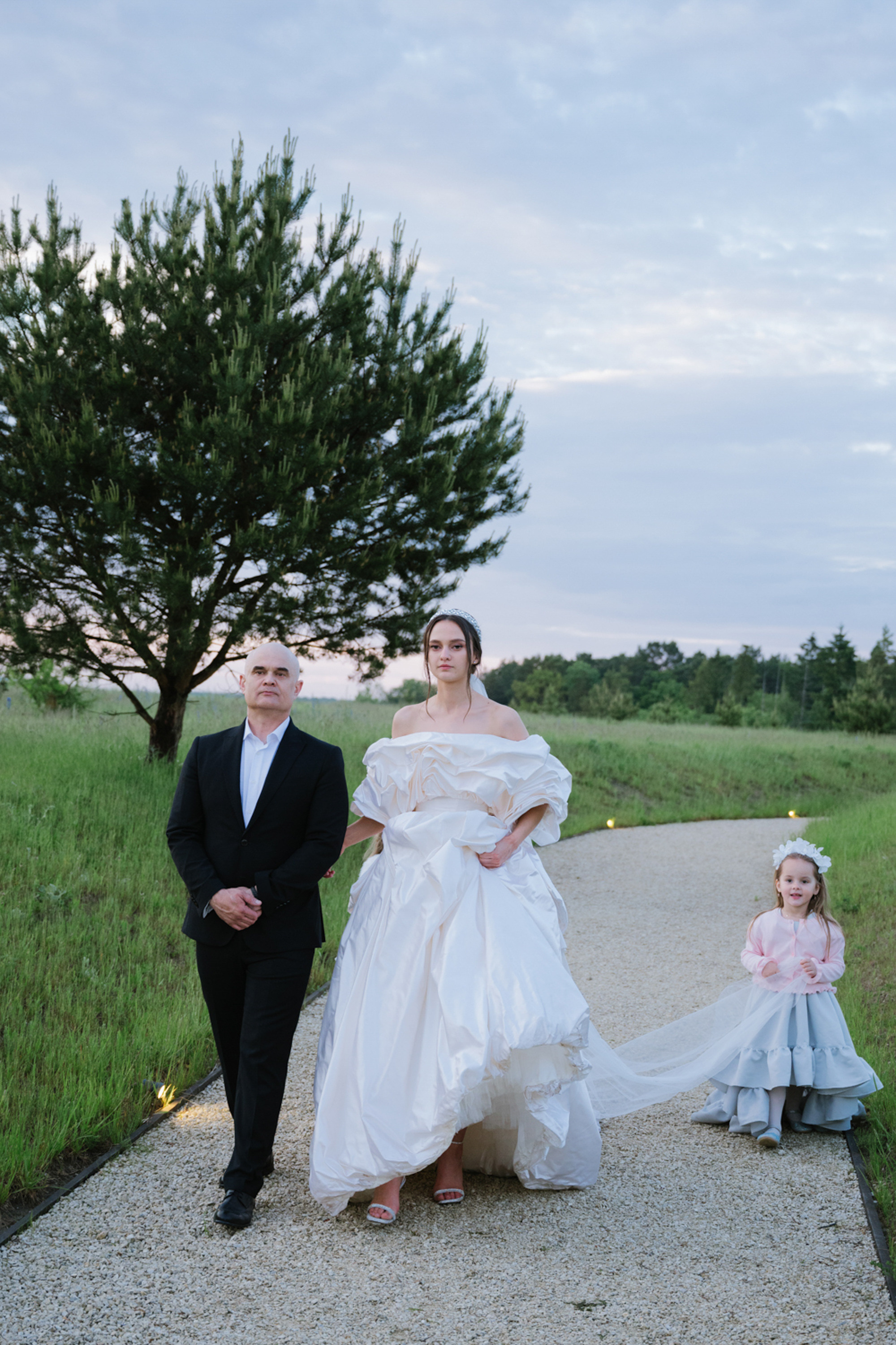 a bride and groom walking down a gravel path