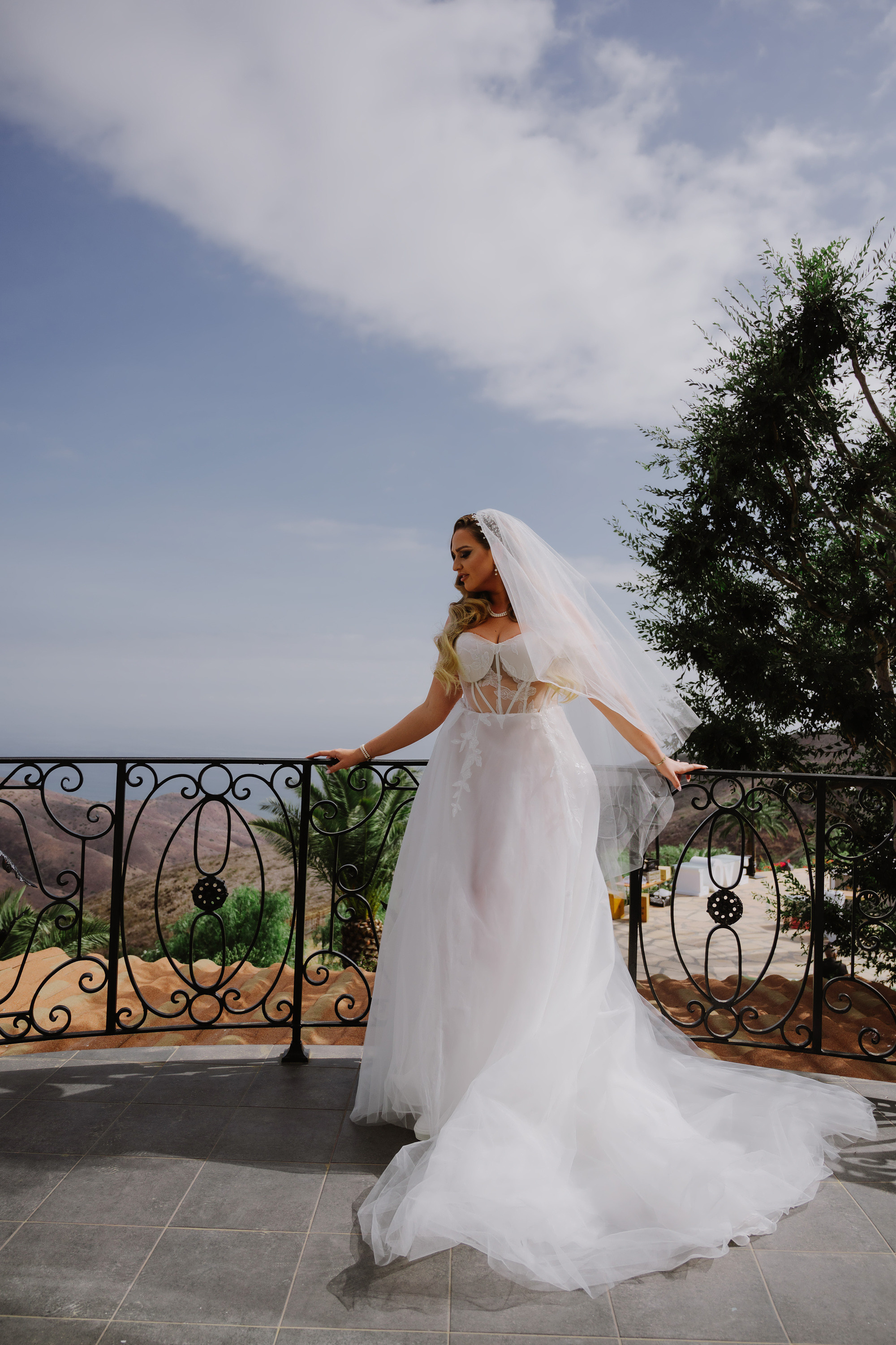 a bride standing on a balcony looking out at the ocean
