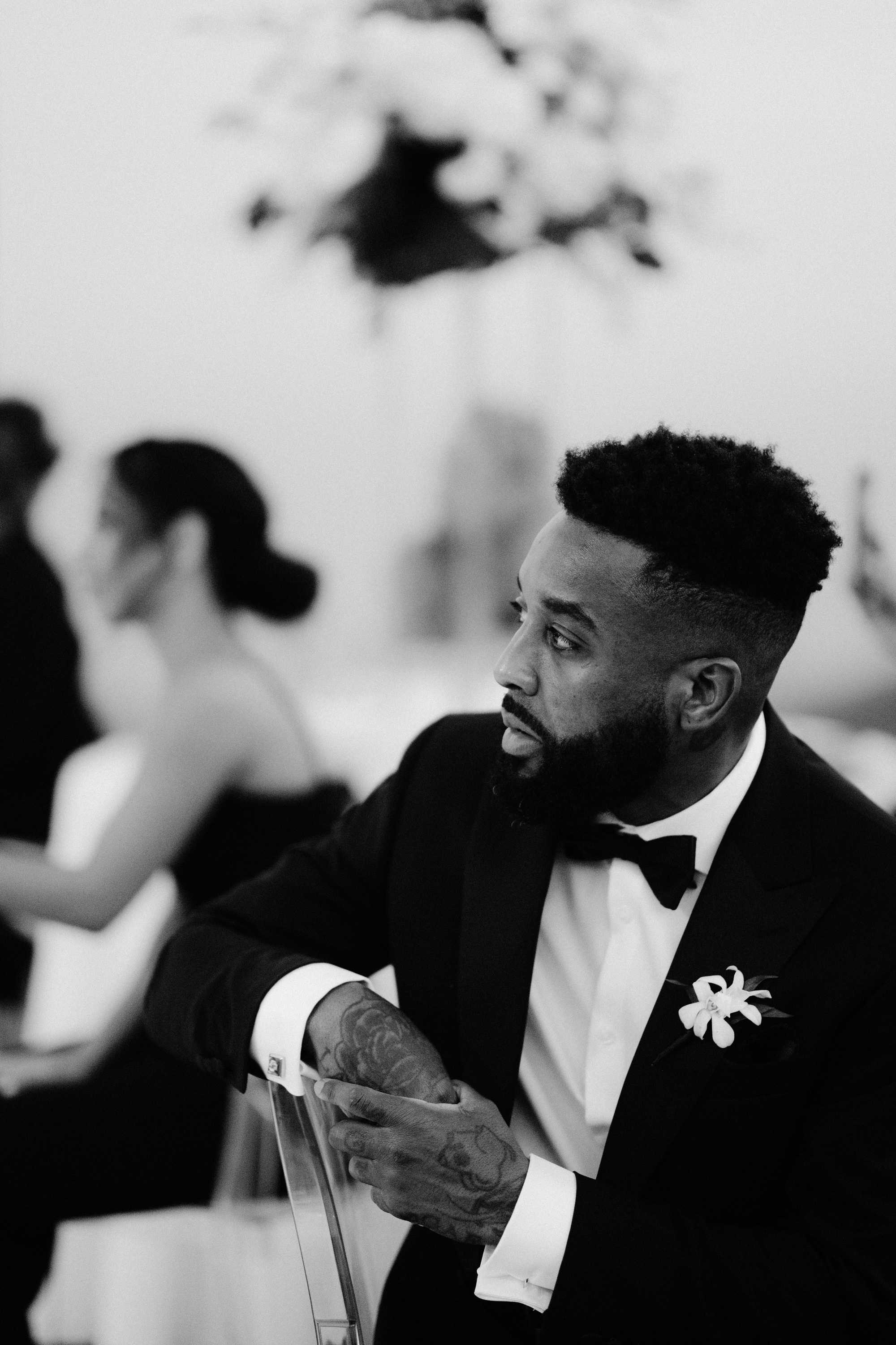 a man in a tuxed suit sitting in a chair