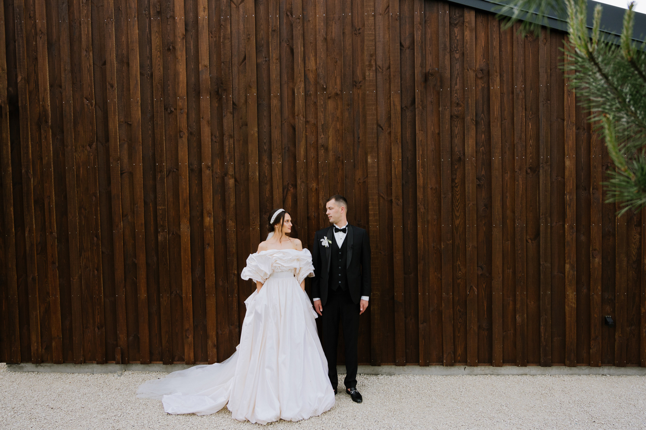 a bride and groom standing in front of a wooden fence