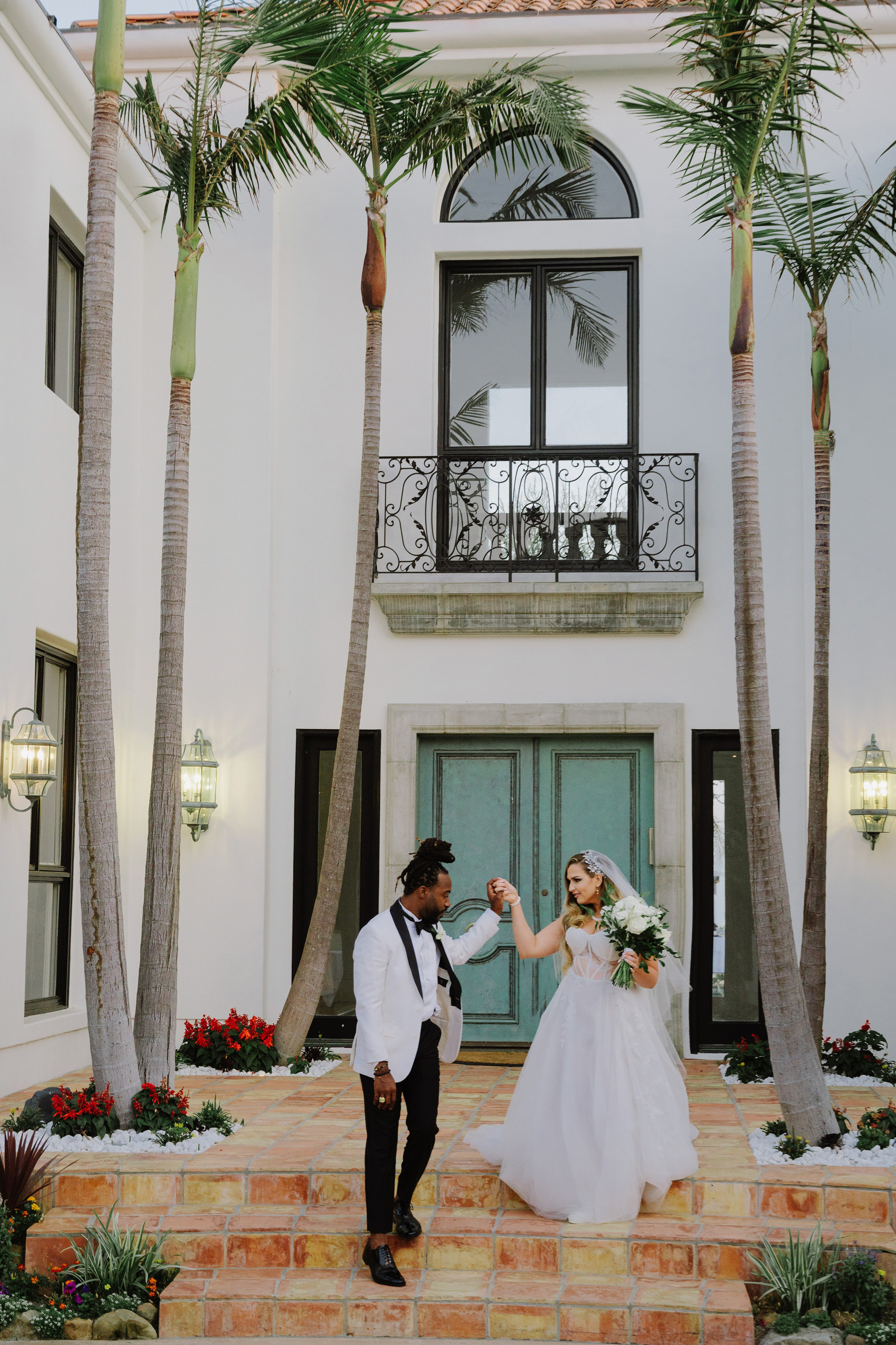 a bride and groom are posing on the steps of a house