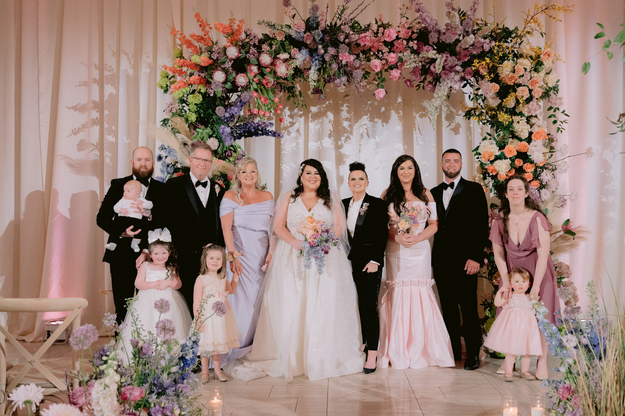 a group of people standing in front of a wedding arch