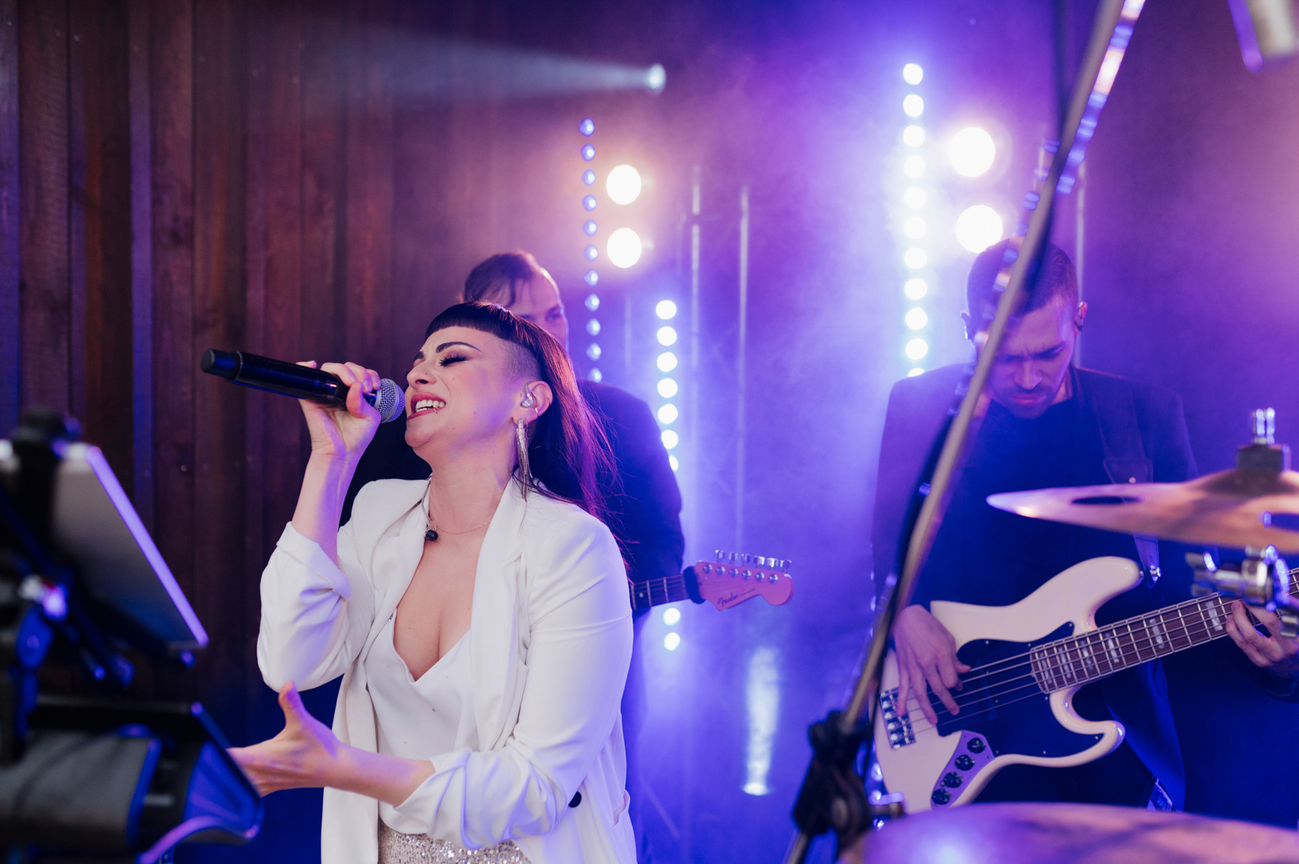 a woman singing into a microphone while a man plays guitar behind her