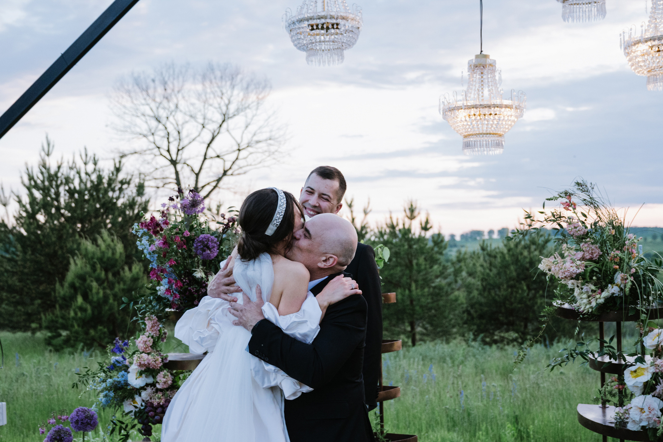 a bride and groom kiss in front of a wedding arch