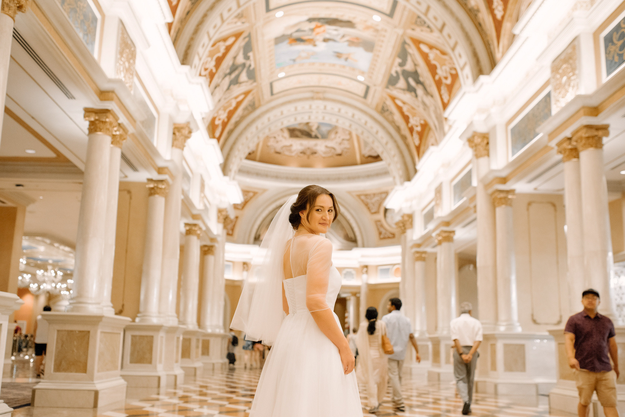 a bride in a white dress standing in a large hall