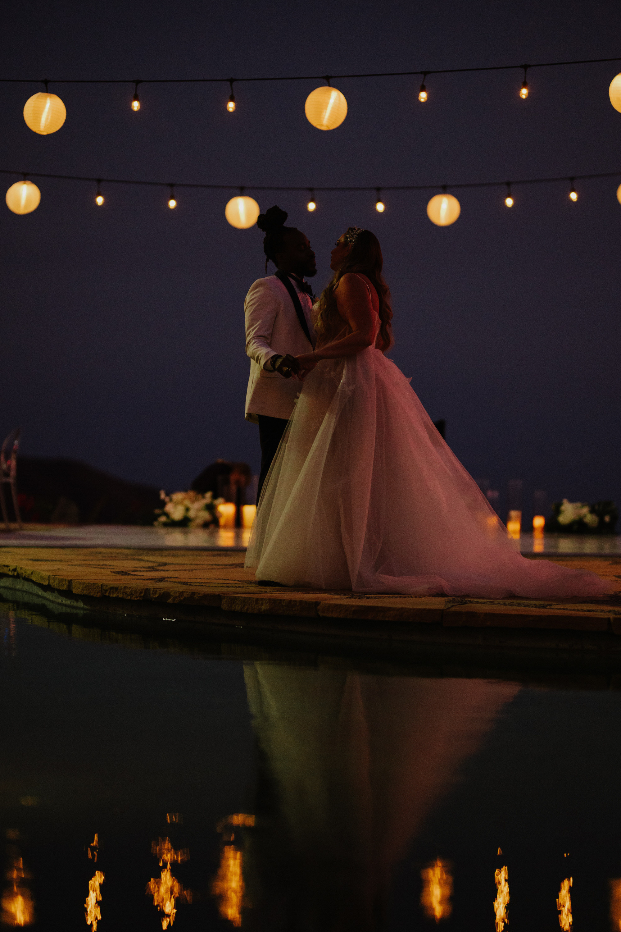 a bride and groom kissing in front of lanterns