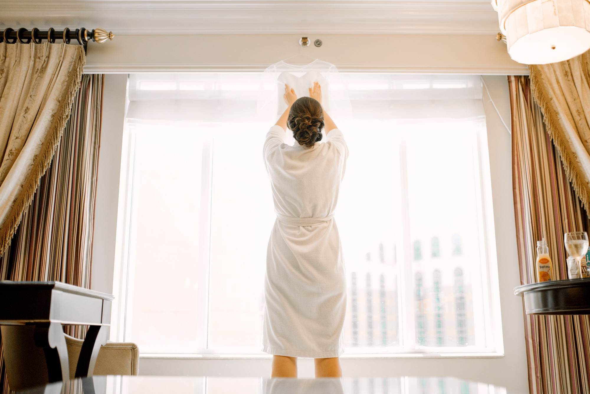 a woman in a bathrobe standing in front of a window