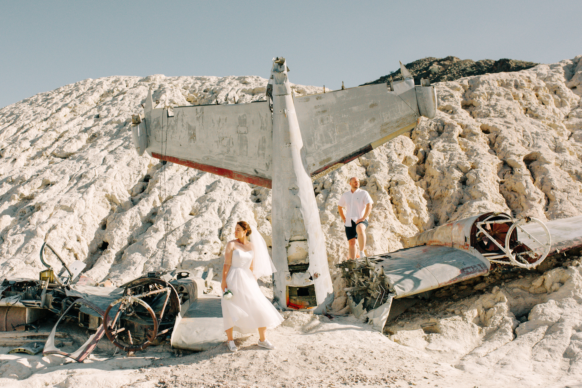 a couple standing next to a plane on a mountain