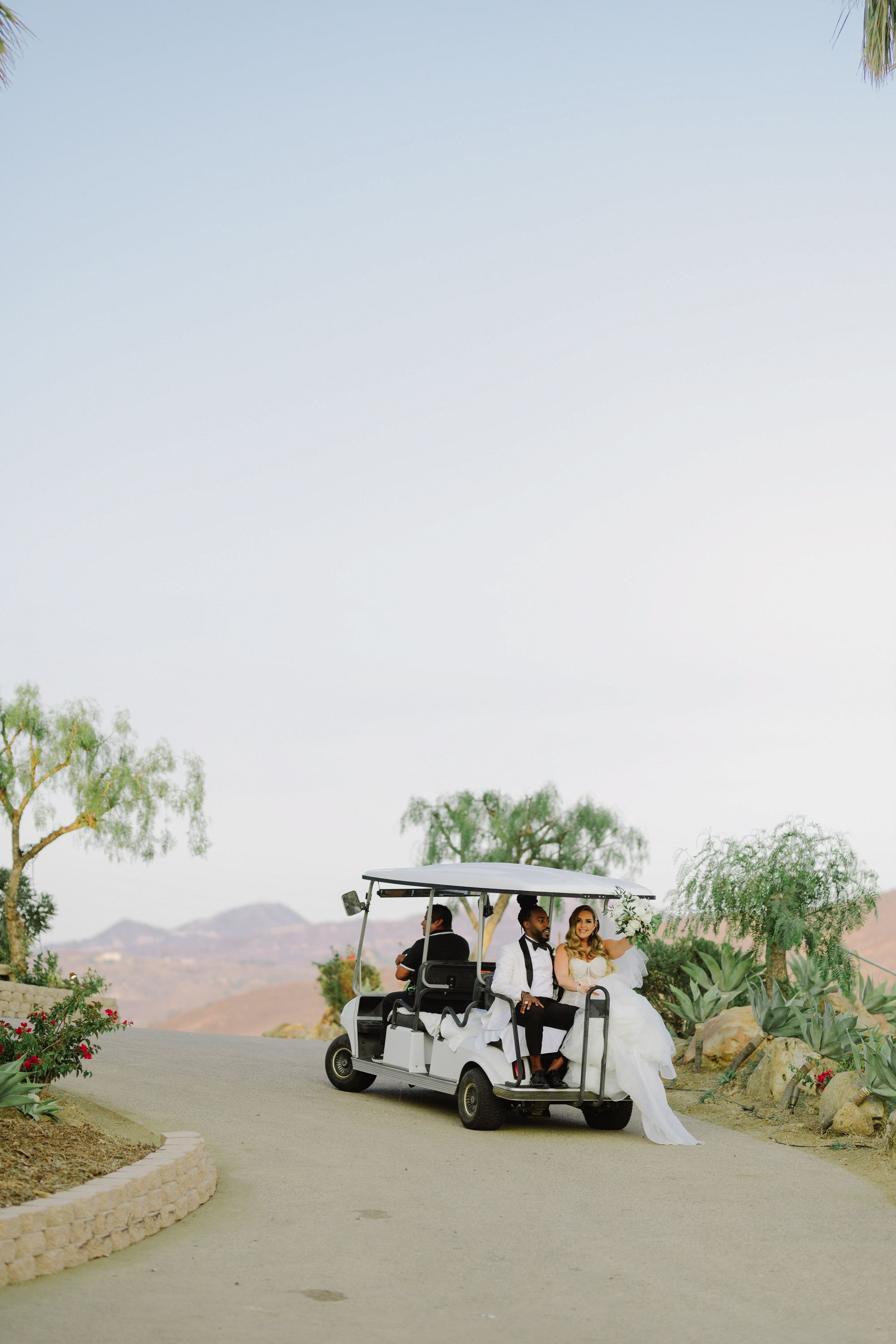 a bride and groom in a golf cart