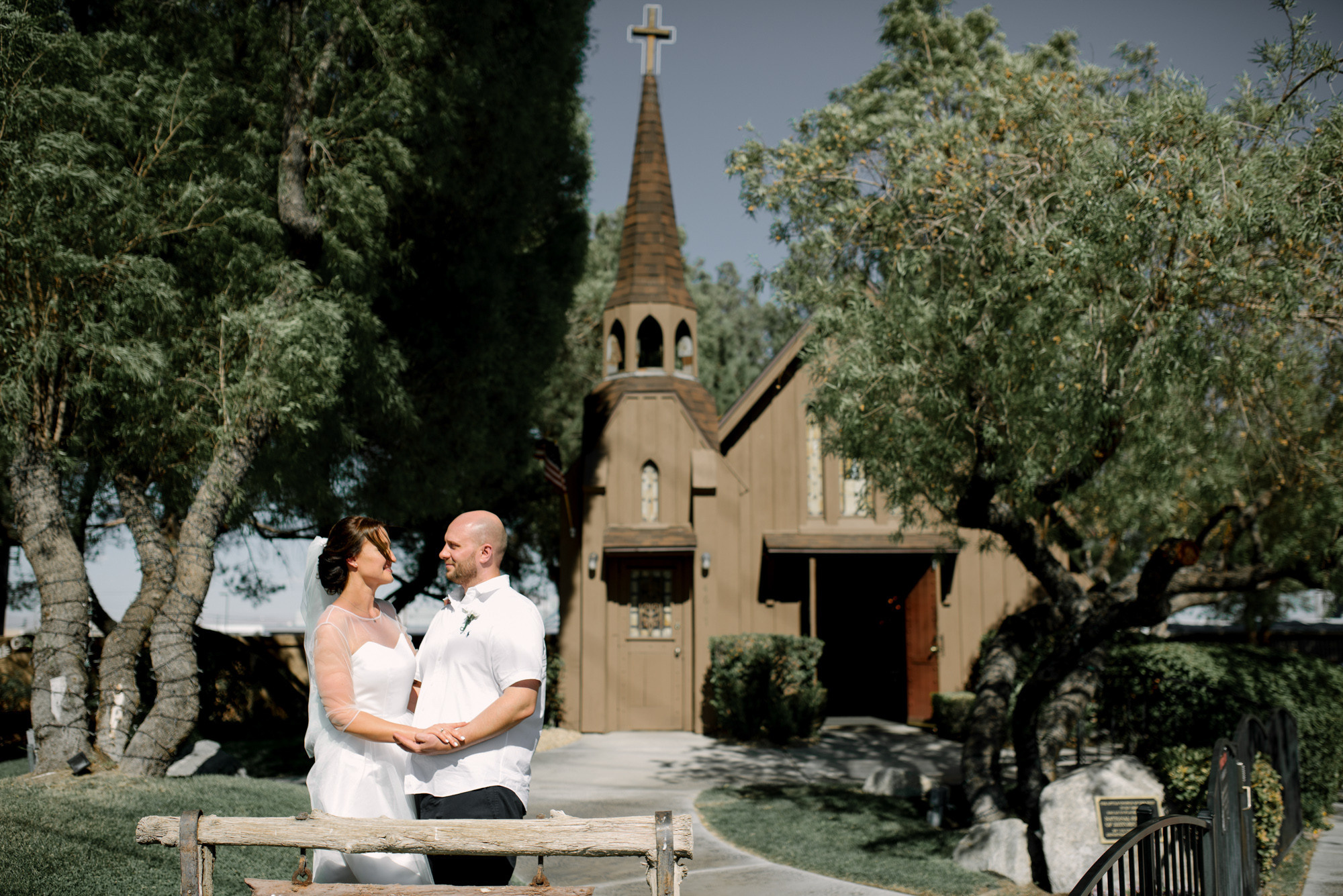 a couple sitting on a bench in front of a church